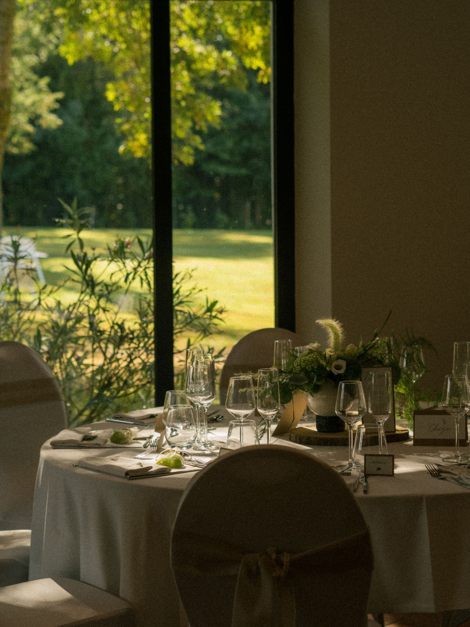 Salle de réception lumineuse avec tables rondes et vue sur jardin vert