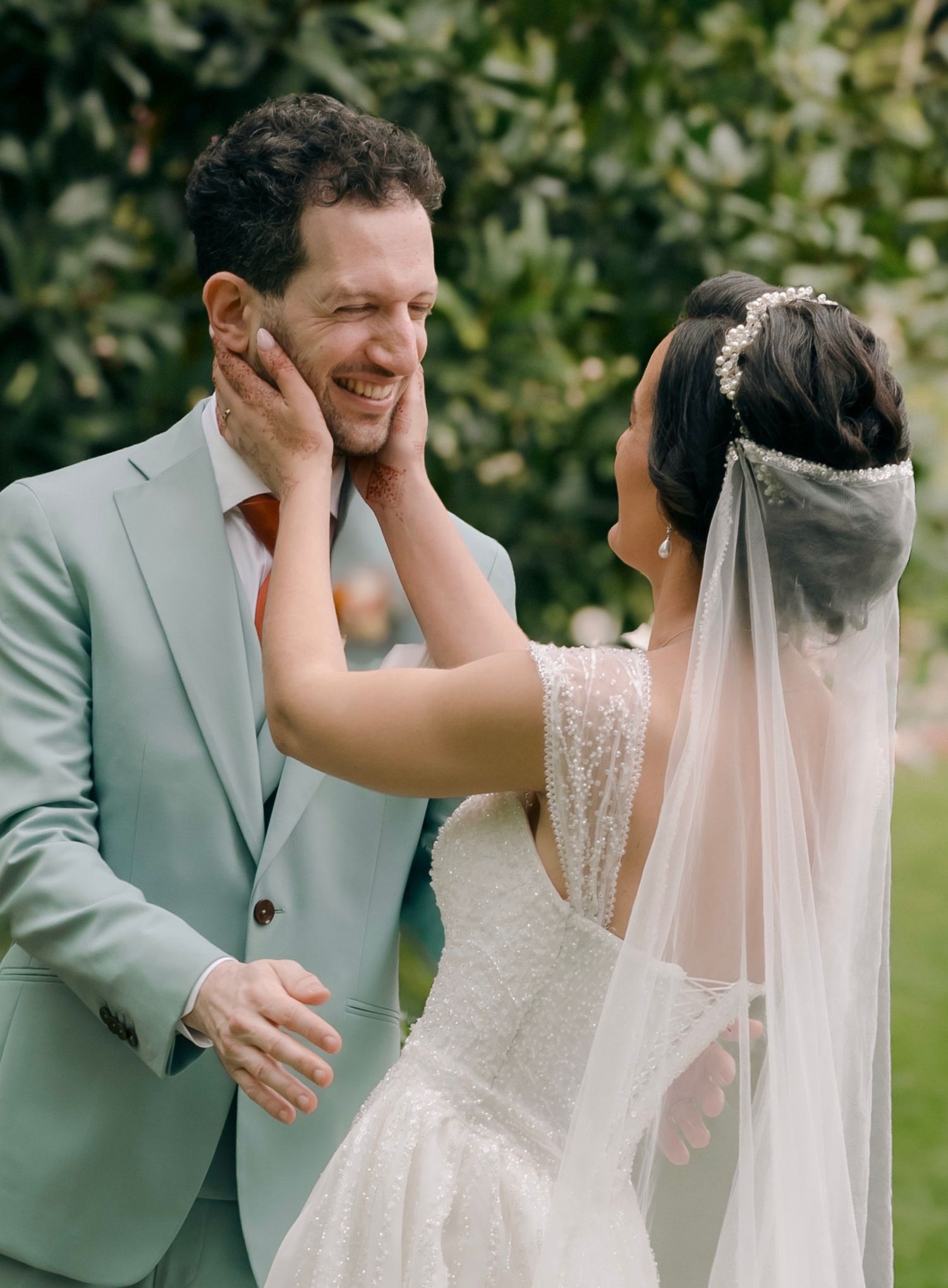 A couple shares an emotional first look moment in their wedding attire on a sunny lawn.