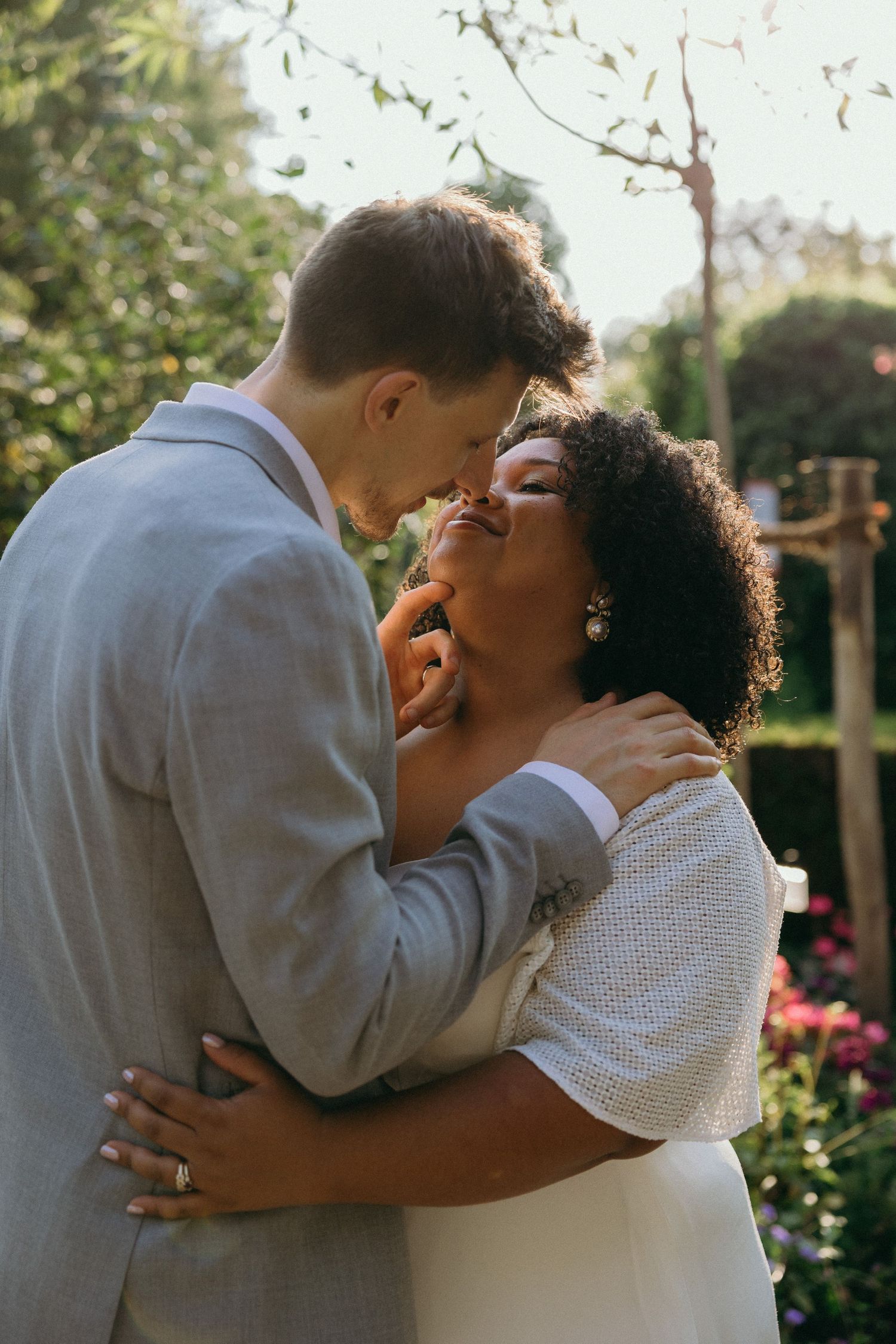 Romantic couple embracing in a garden during a wedding photoshoot sequence.