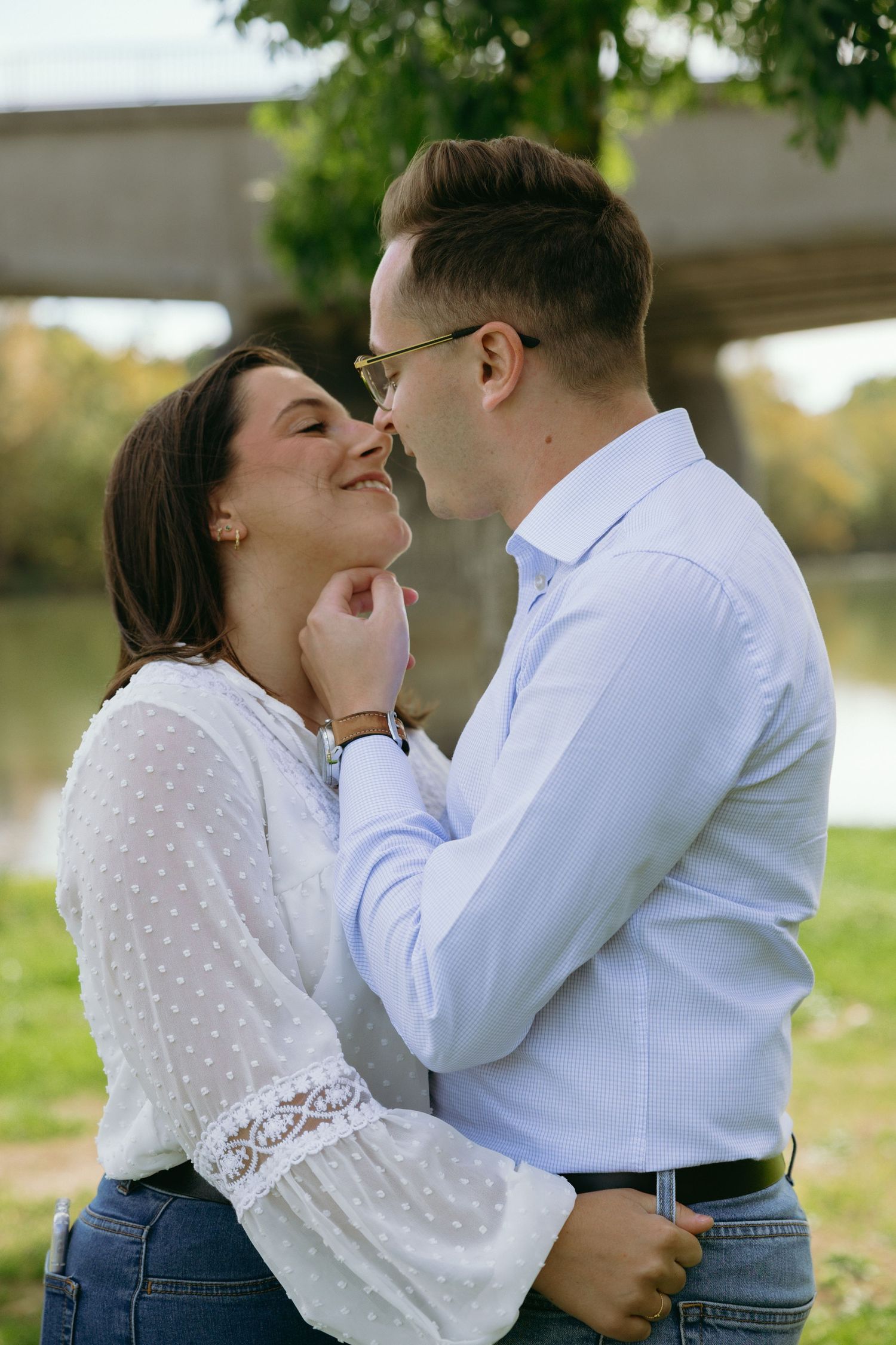Romantic couple sharing an intimate moment outdoors in casual attire against a natural background.