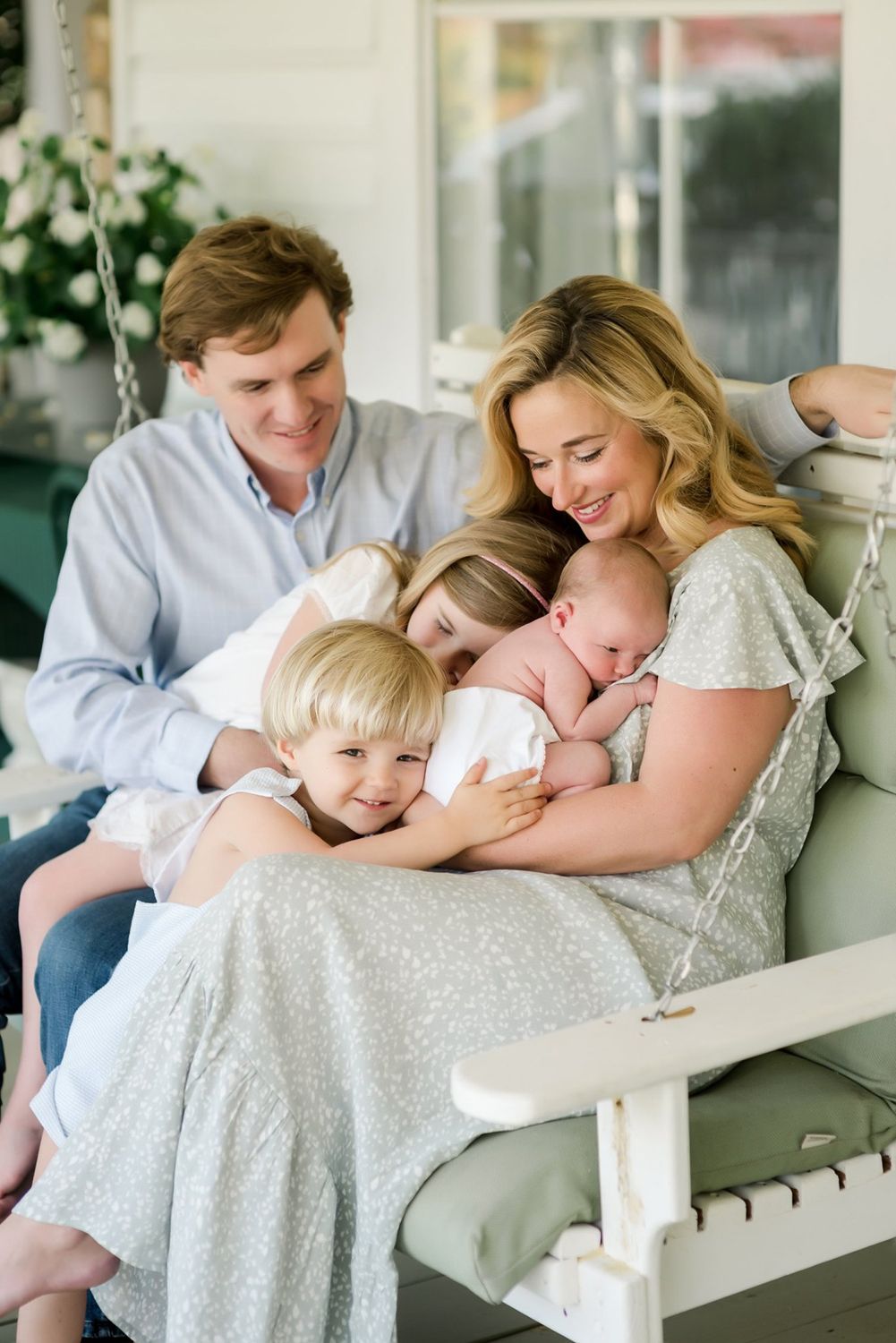 A family shares a warm moment together while relaxing on a front porch swing.