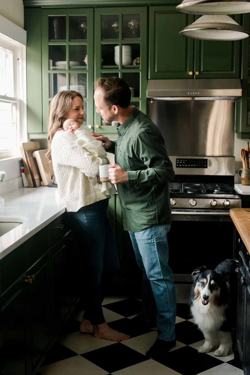 Couple dancing in green kitchen with dog watching nearby.
