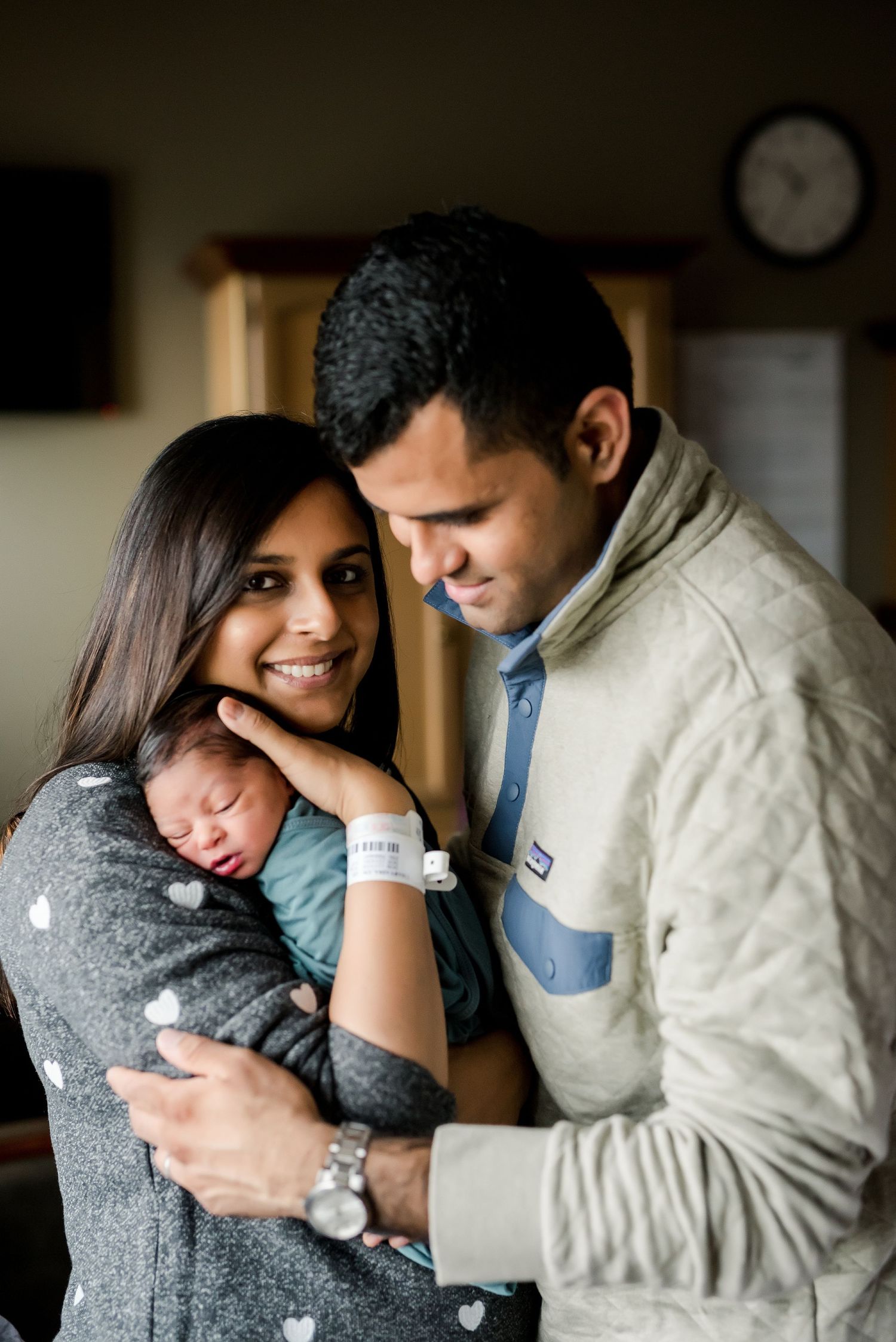 A couple cradles their newborn baby while sharing an intimate moment together.