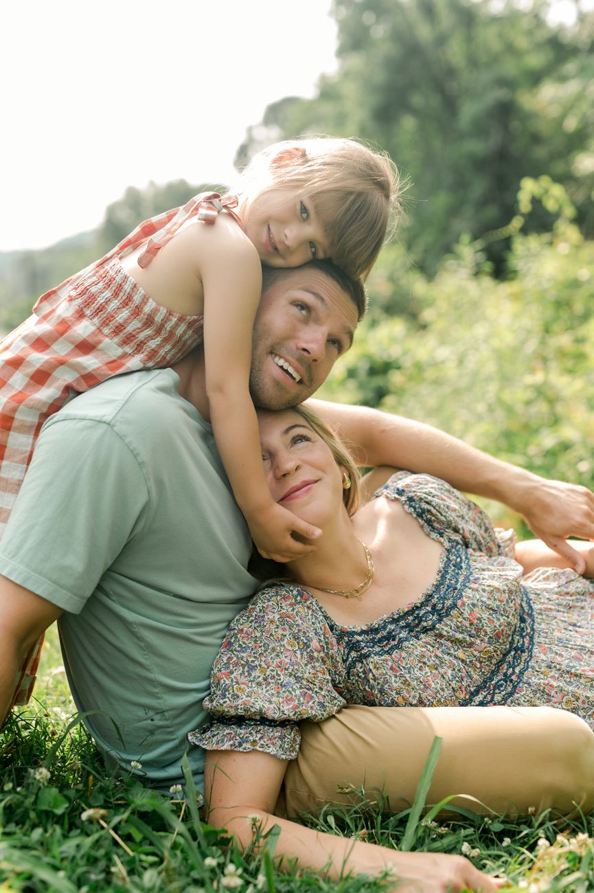 Candid moments of family bonding while laying in green grass during summer.