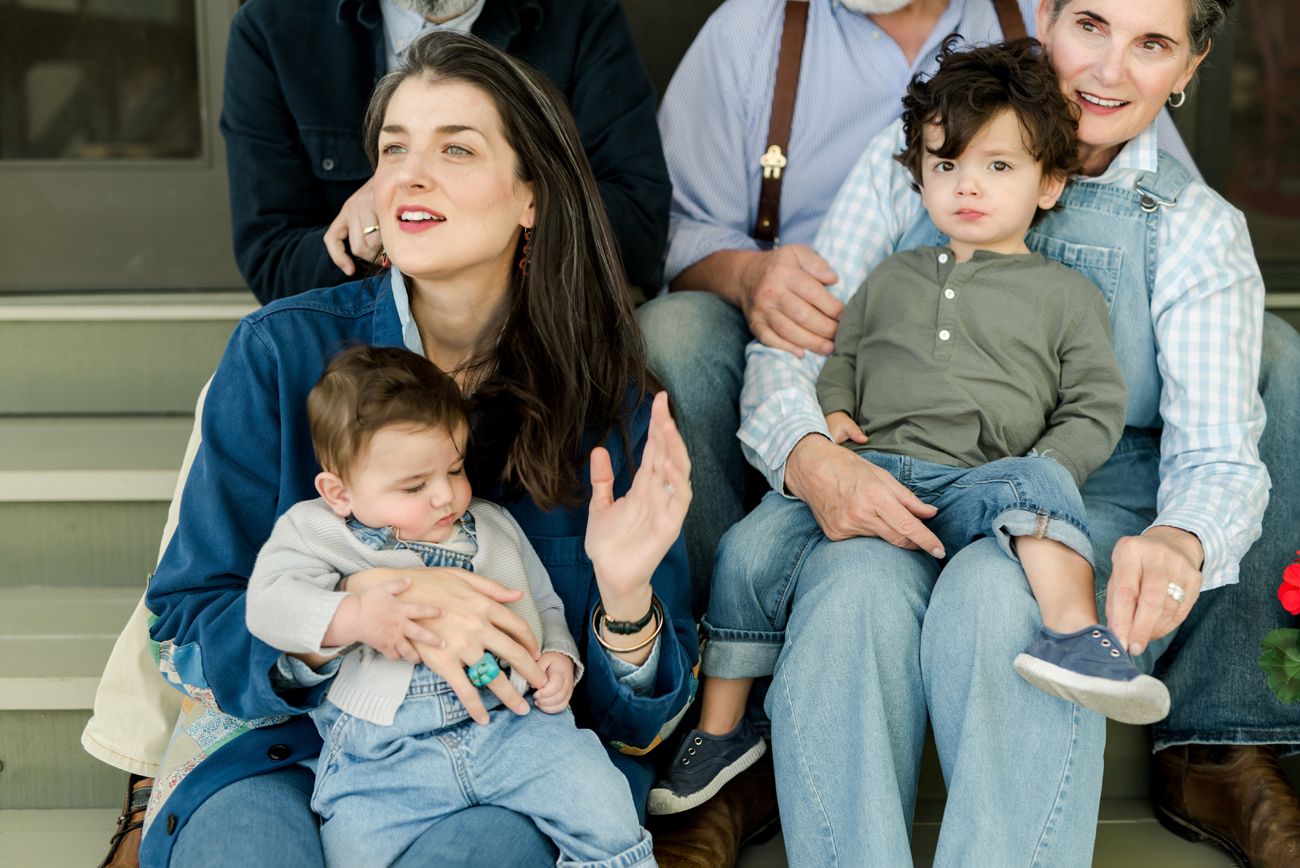 A casual family gathering on outdoor steps with babies and casual denim outfits.