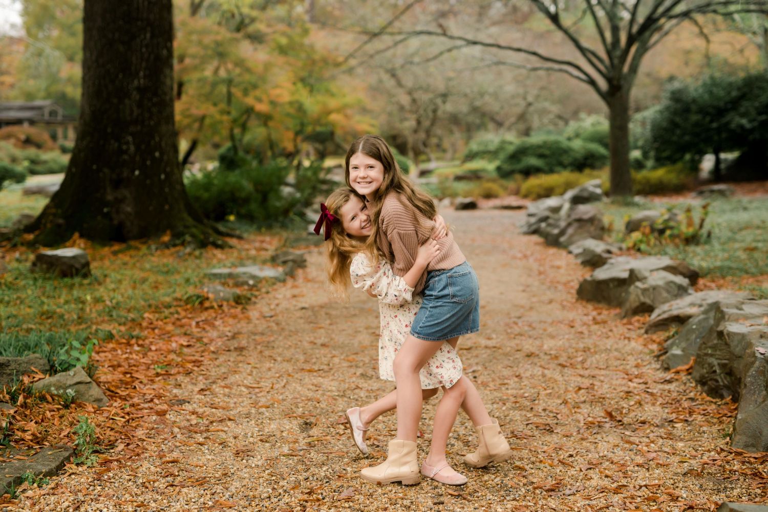 A playful moment captured on a autumn path with fallen leaves and trees in the background.