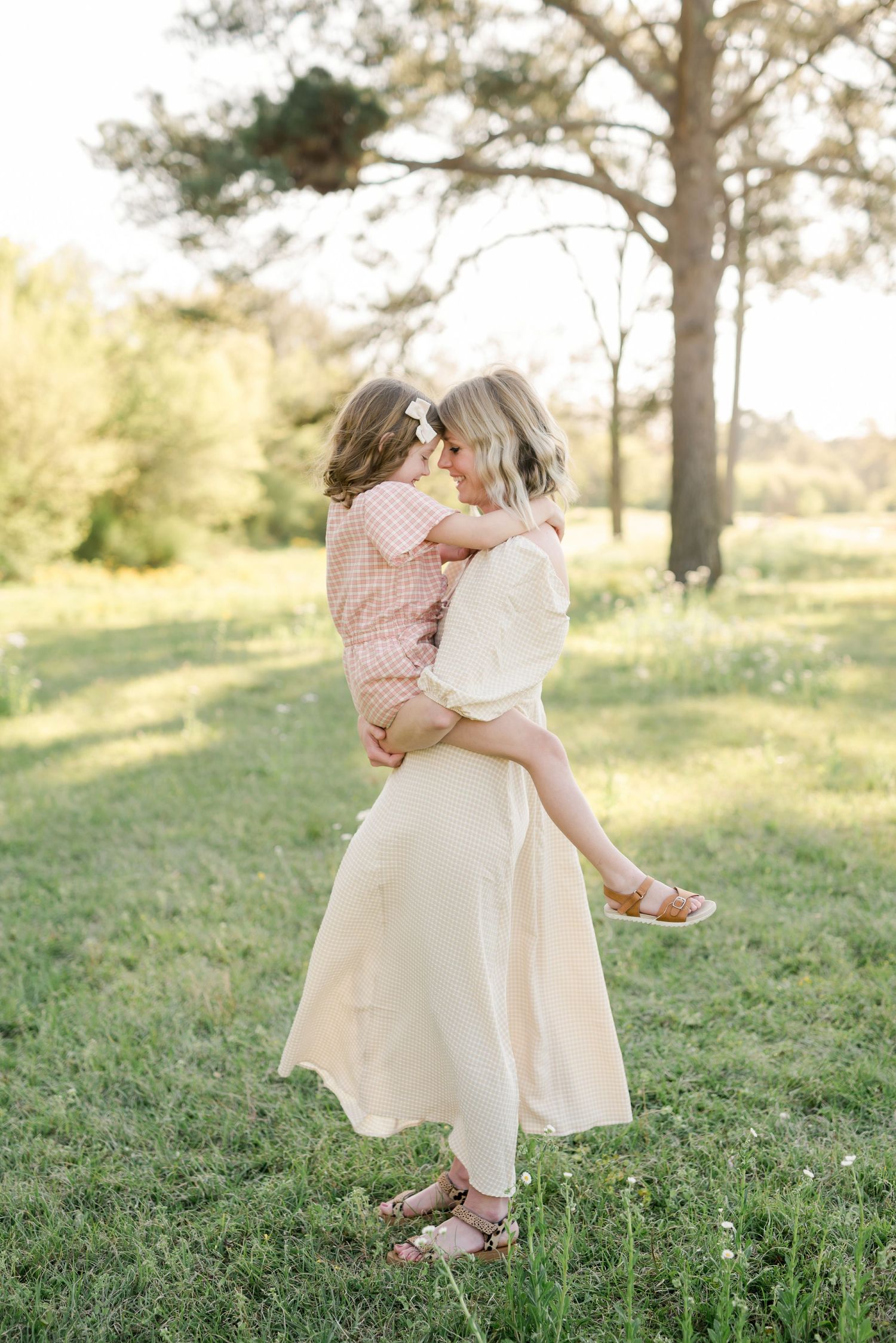 A tender moment captured as parent and child embrace while spinning in a sunlit field.