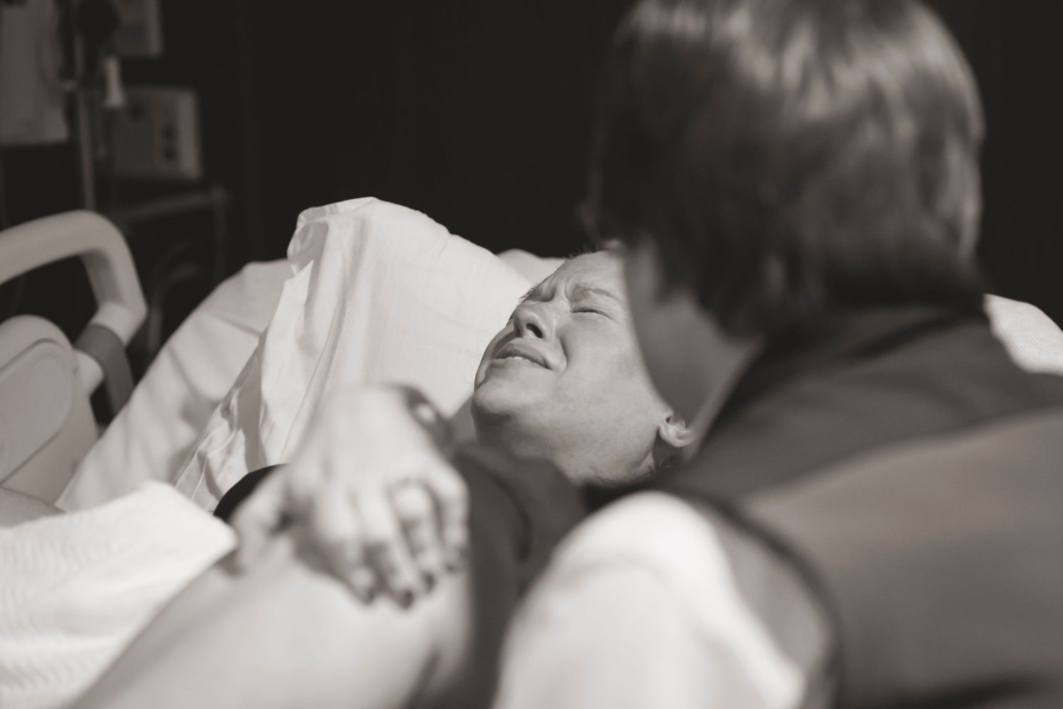 Black and white image showing intense moments during labor in a hospital setting.