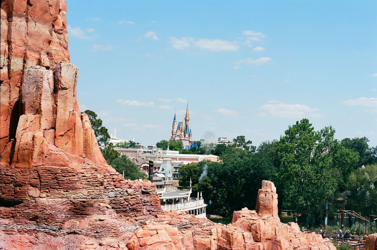 View of Cinderella Castle from Big Thunder Mountain with red rock formations in foreground.