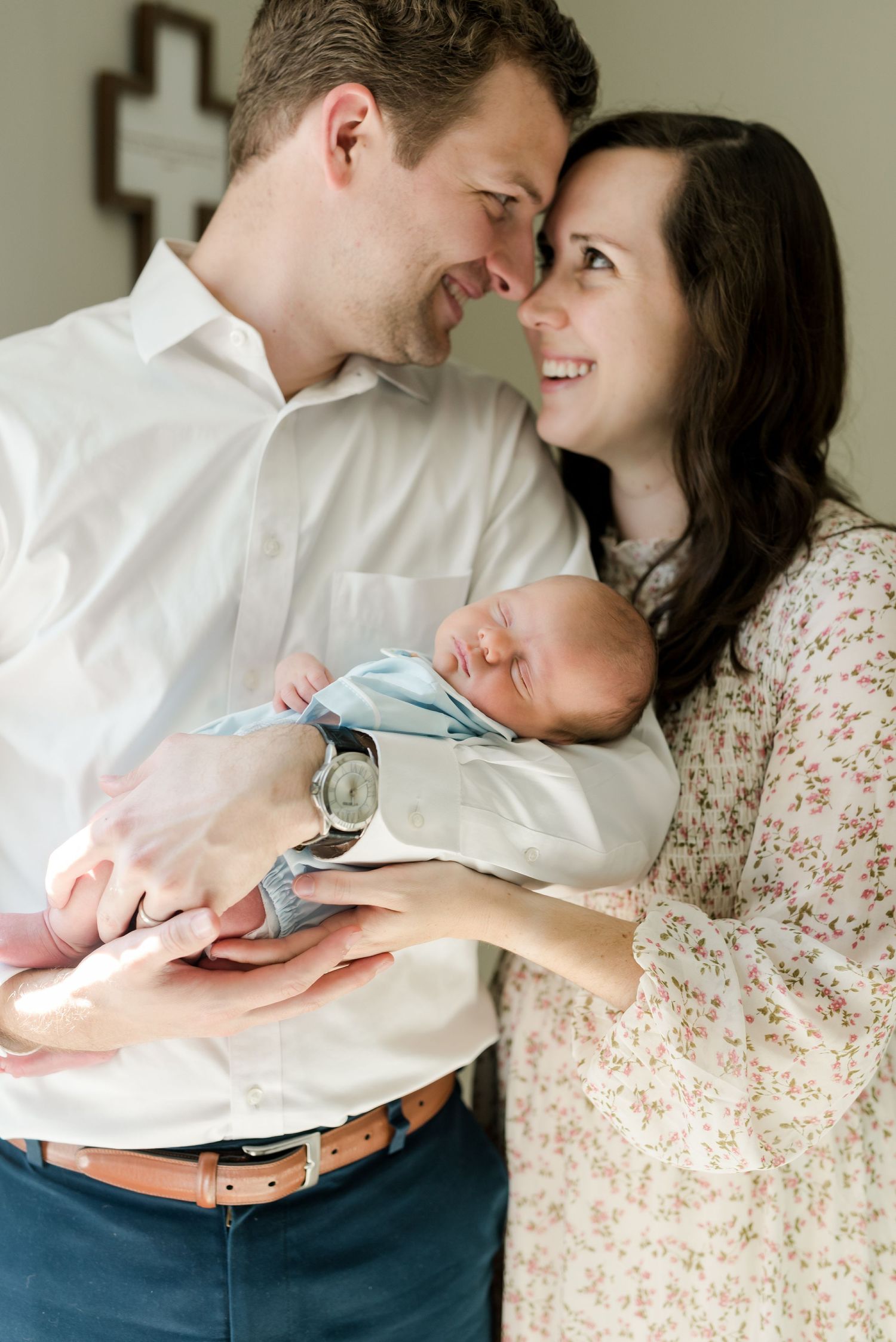 Intimate family portrait with parents cradling newborn baby while sharing tender moment.
