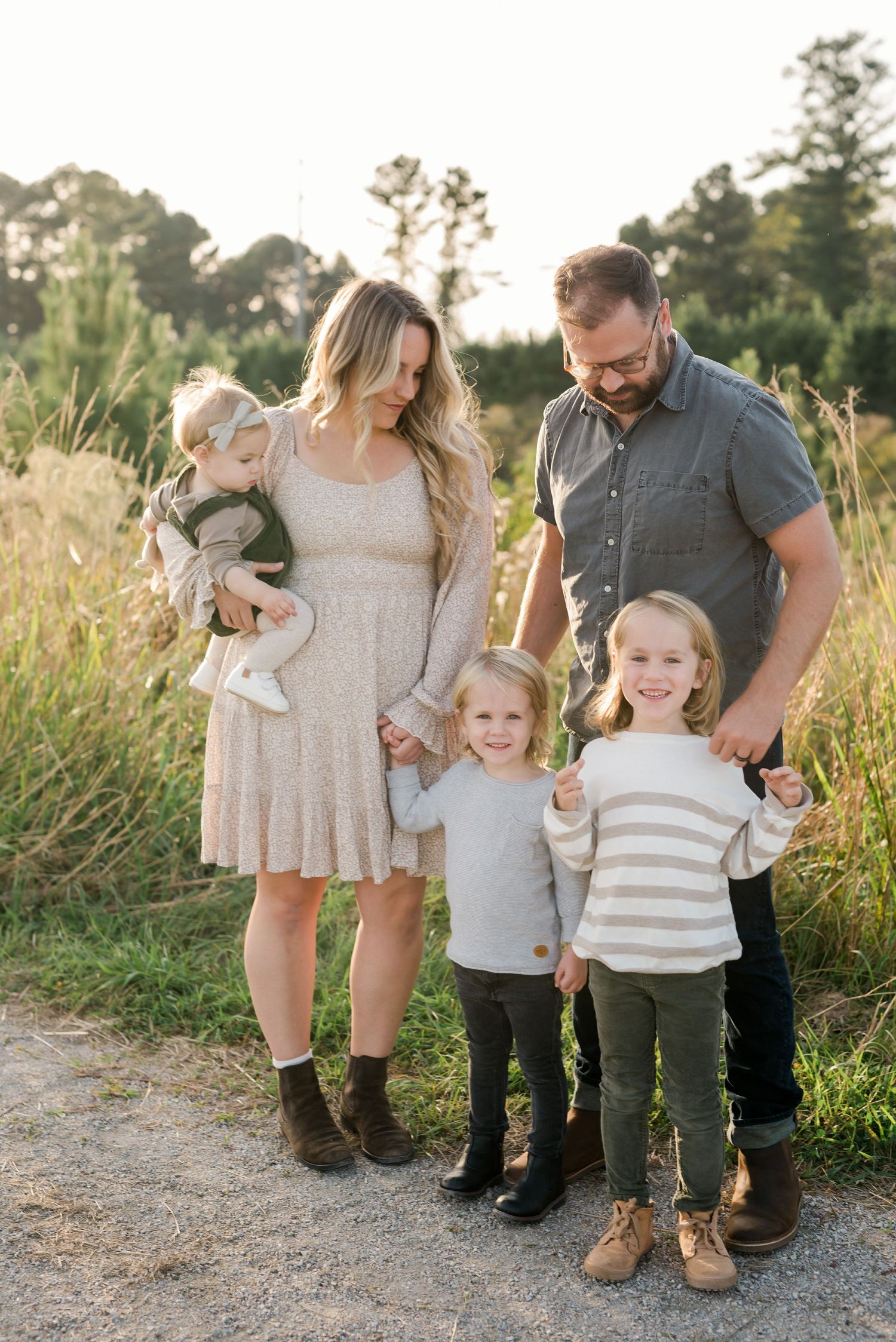 Beautiful family portrait taken on a nature path during golden hour with tall grass in background.