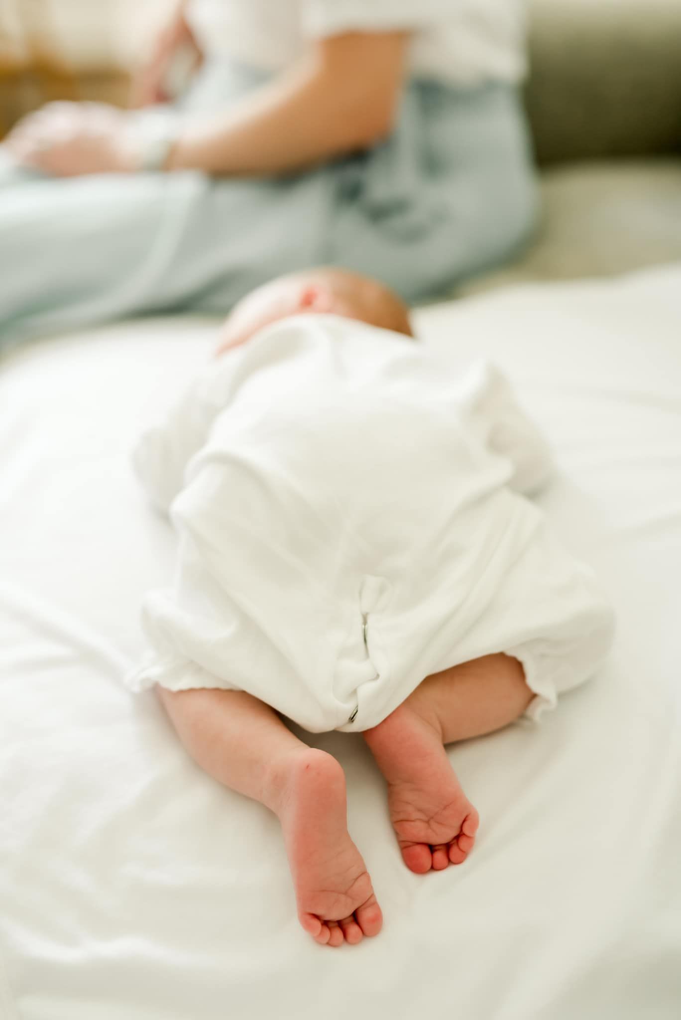 Close-up of tiny baby feet wrapped in white blanket on soft bedding.
