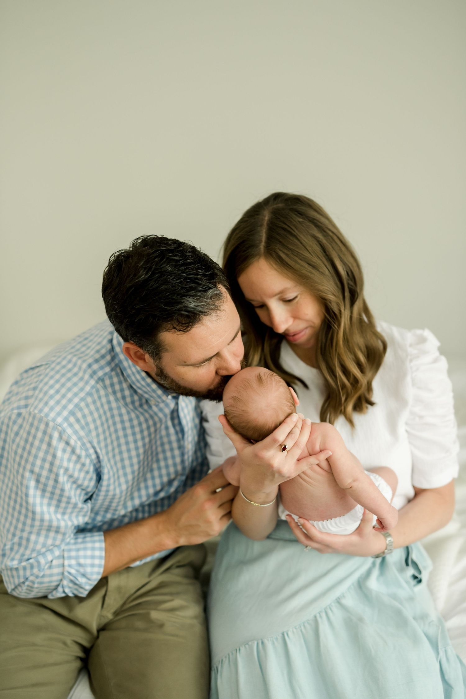 Family sharing an intimate moment together with their newborn baby in soft lighting.