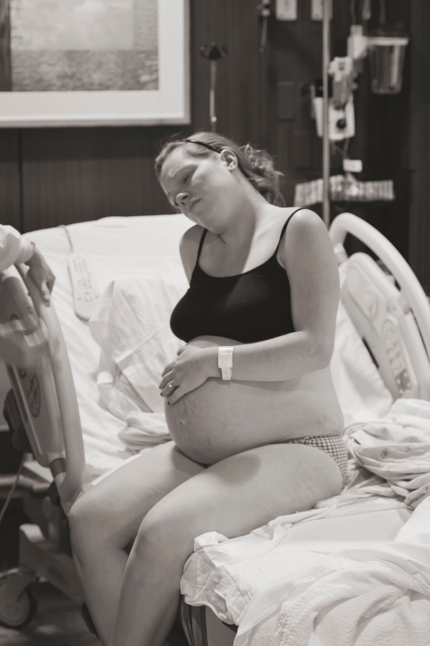 A pregnant patient sits on a hospital bed during active labor contractions.