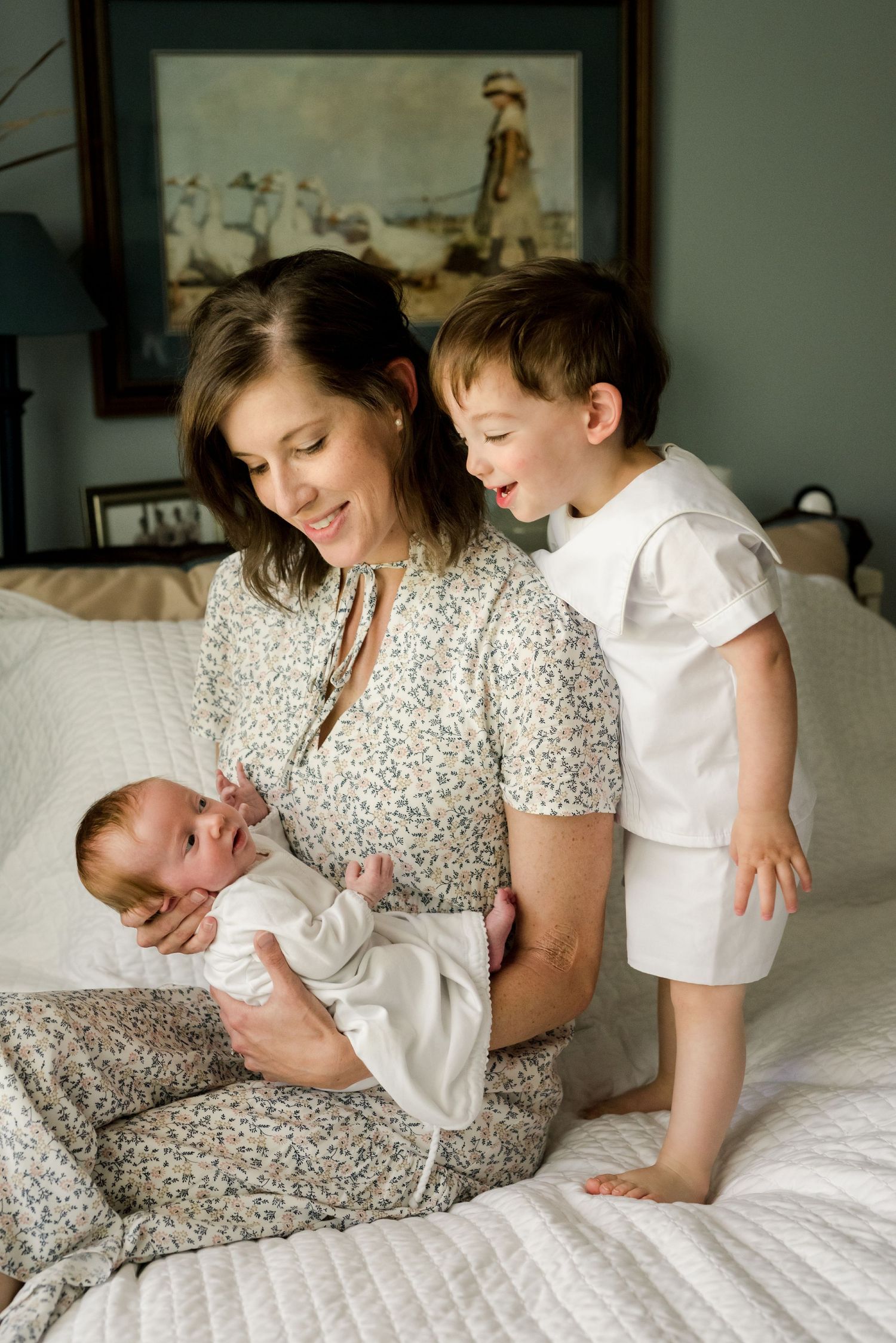 A heartwarming family moment on a bed with a newborn and toddler.