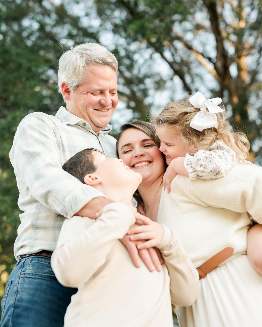 Joyful family embrace outdoors with warm evening light.