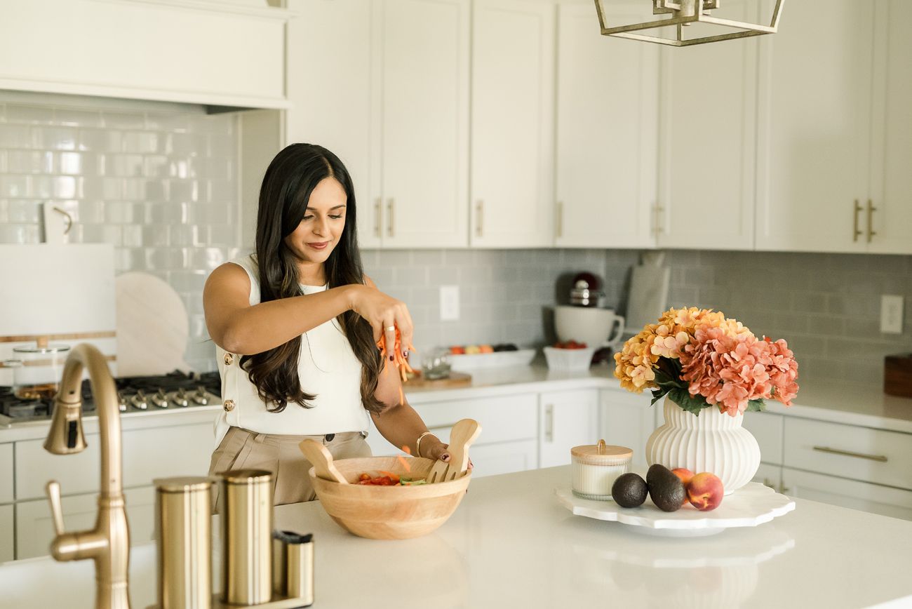 Modern white kitchen interior with fresh flowers and cooking preparations on counter.