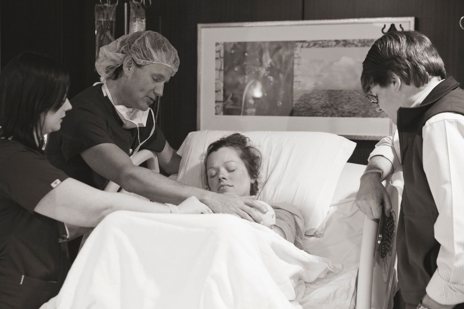 Medical staff attend to a patient lying in a hospital bed during treatment.