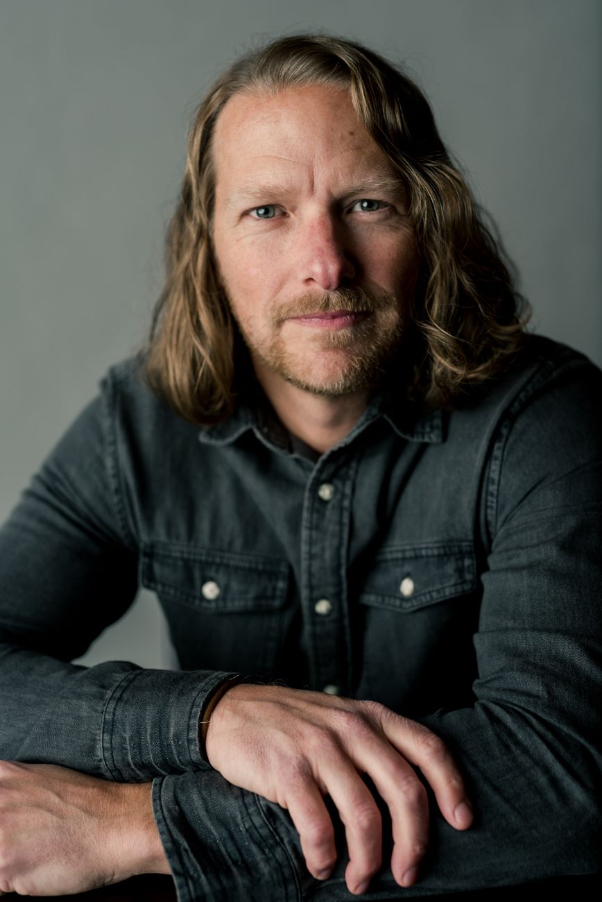 Portrait series in dark denim jacket against grey backdrop showing different poses.