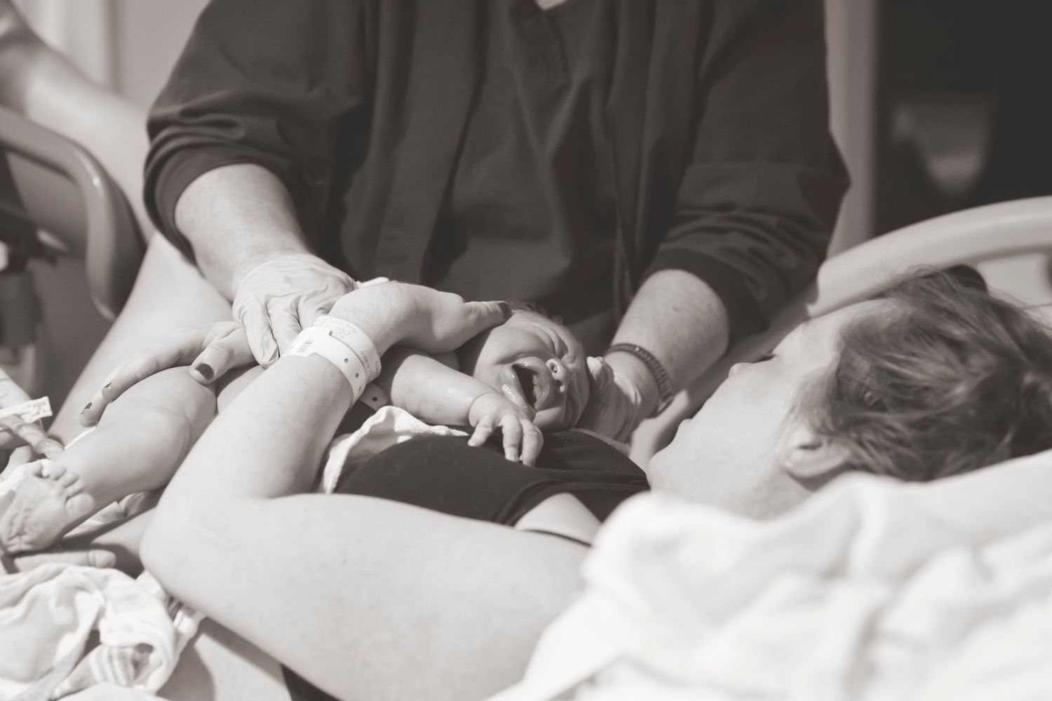 Medical staff providing care during childbirth in black and white photograph.