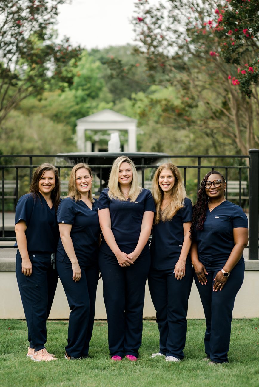Group photo of medical staff wearing matching navy scrubs standing together outdoors.
