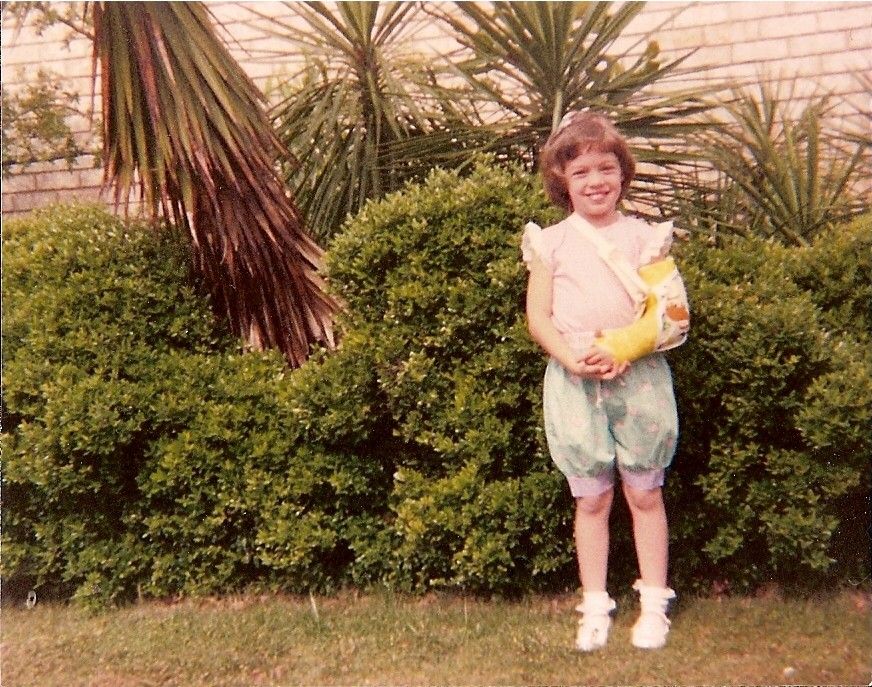 Toddler in colorful clothing playing in front of palm trees and bushes.