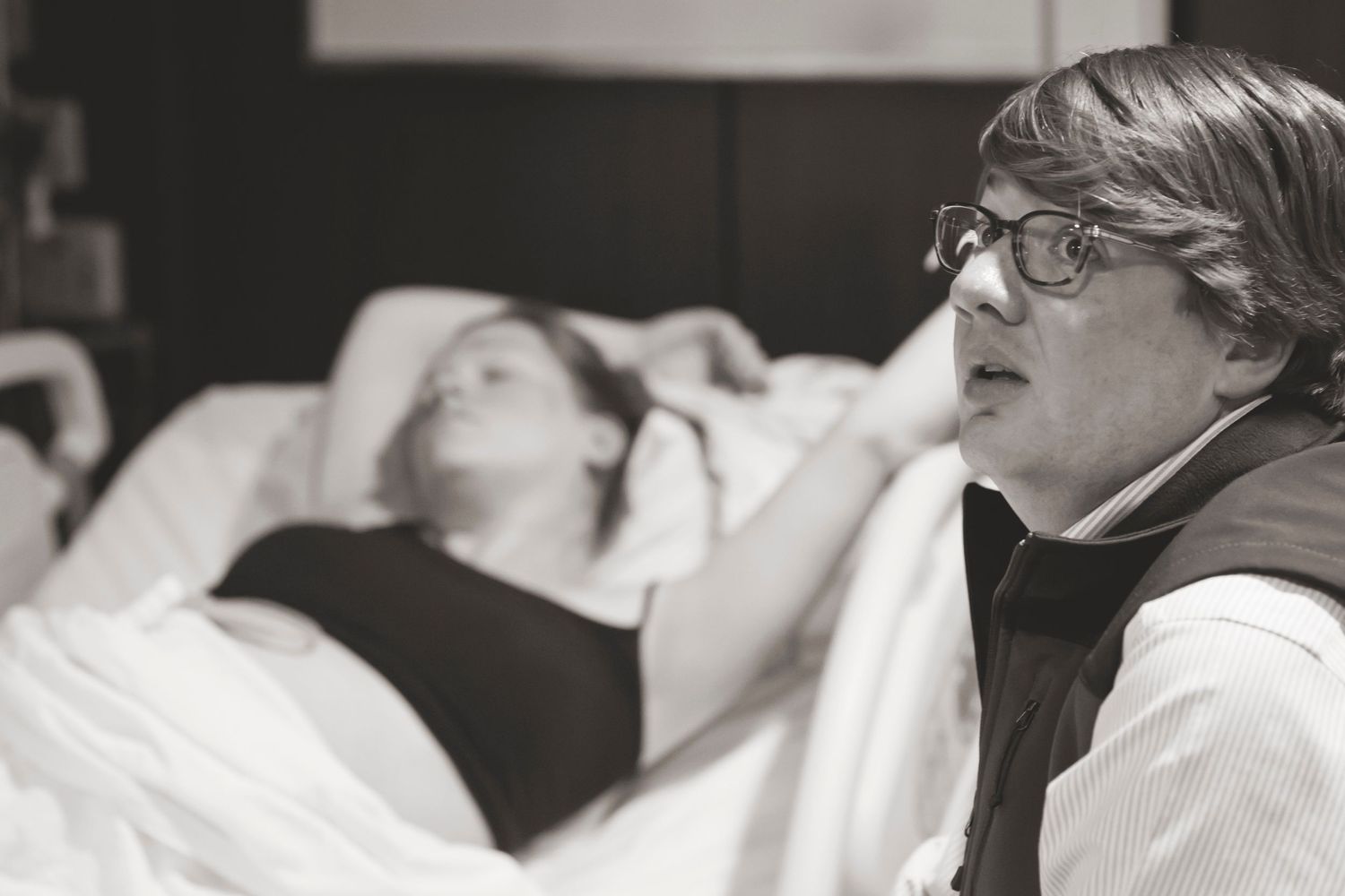 Black and white image showing emotional moments during childbirth in a hospital room.