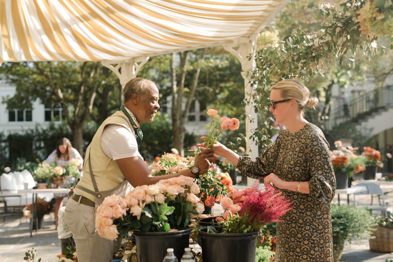 Event setup under striped canopy with floral arrangements and garden decor.