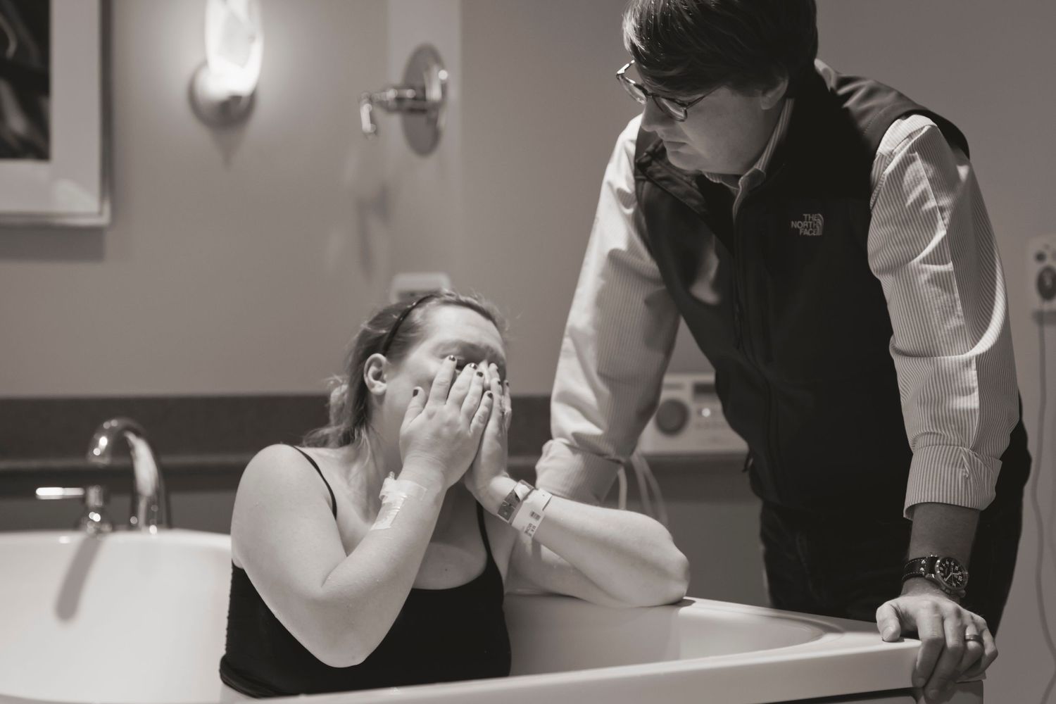 An emotional moment captured during labor as support is provided in a hospital bathroom.