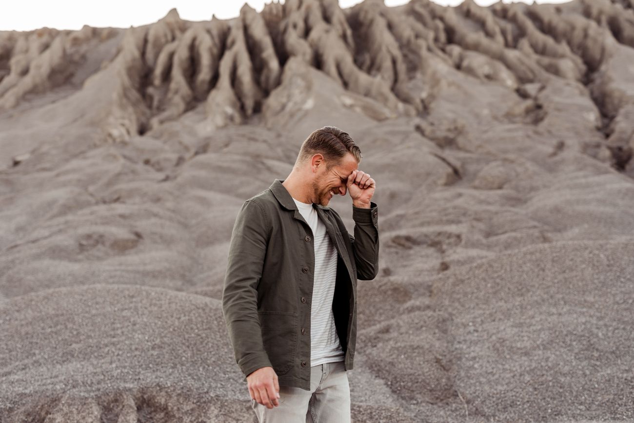 Person in casual attire walking along desert terrain during golden hour.