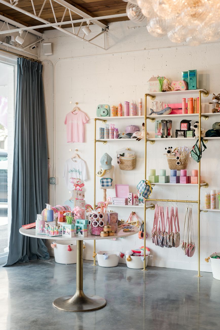 Modern retail space with pink and gold decor featuring shelving displays and teal curtains.