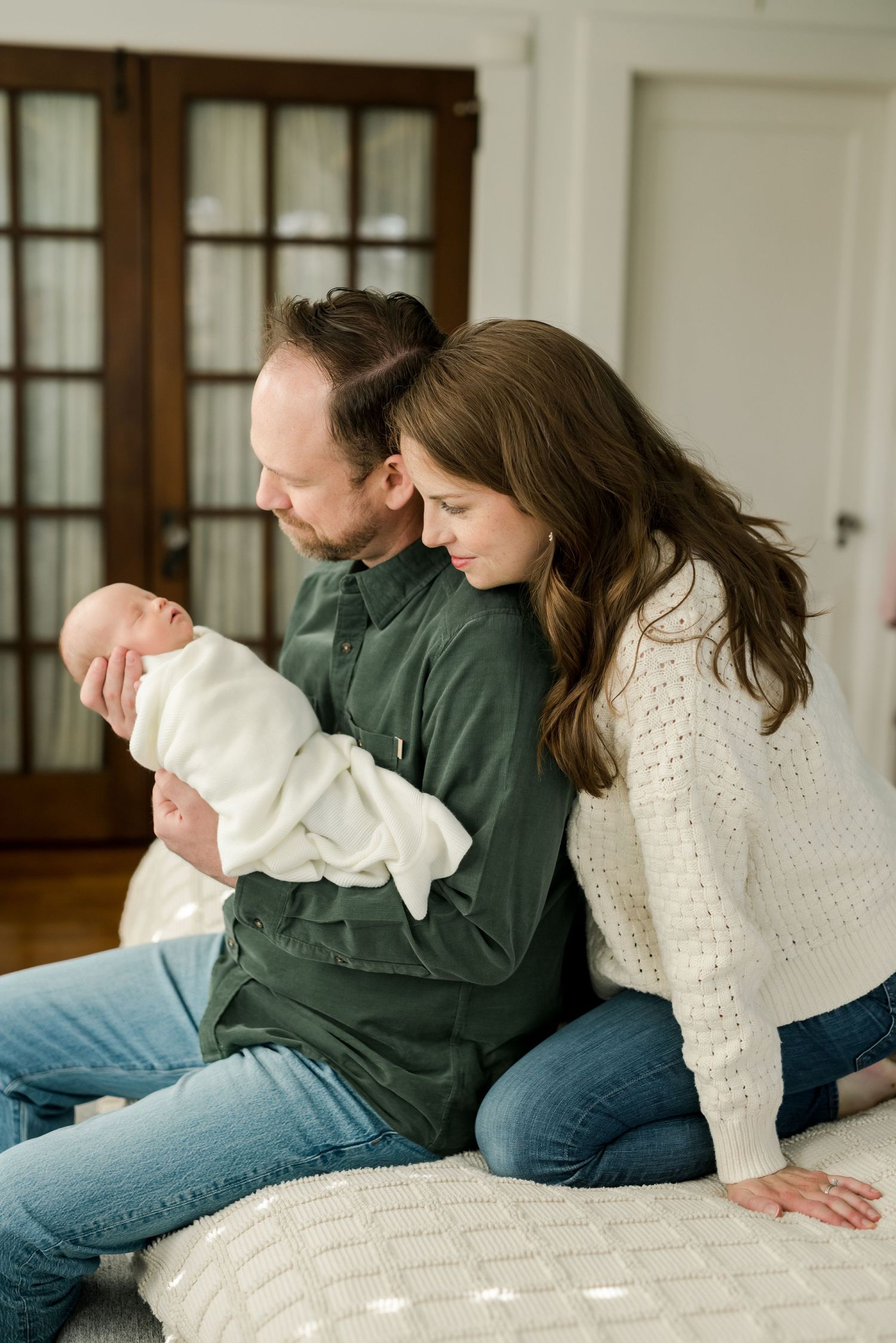 Intimate indoor family moments captured in soft natural light on a white bed.