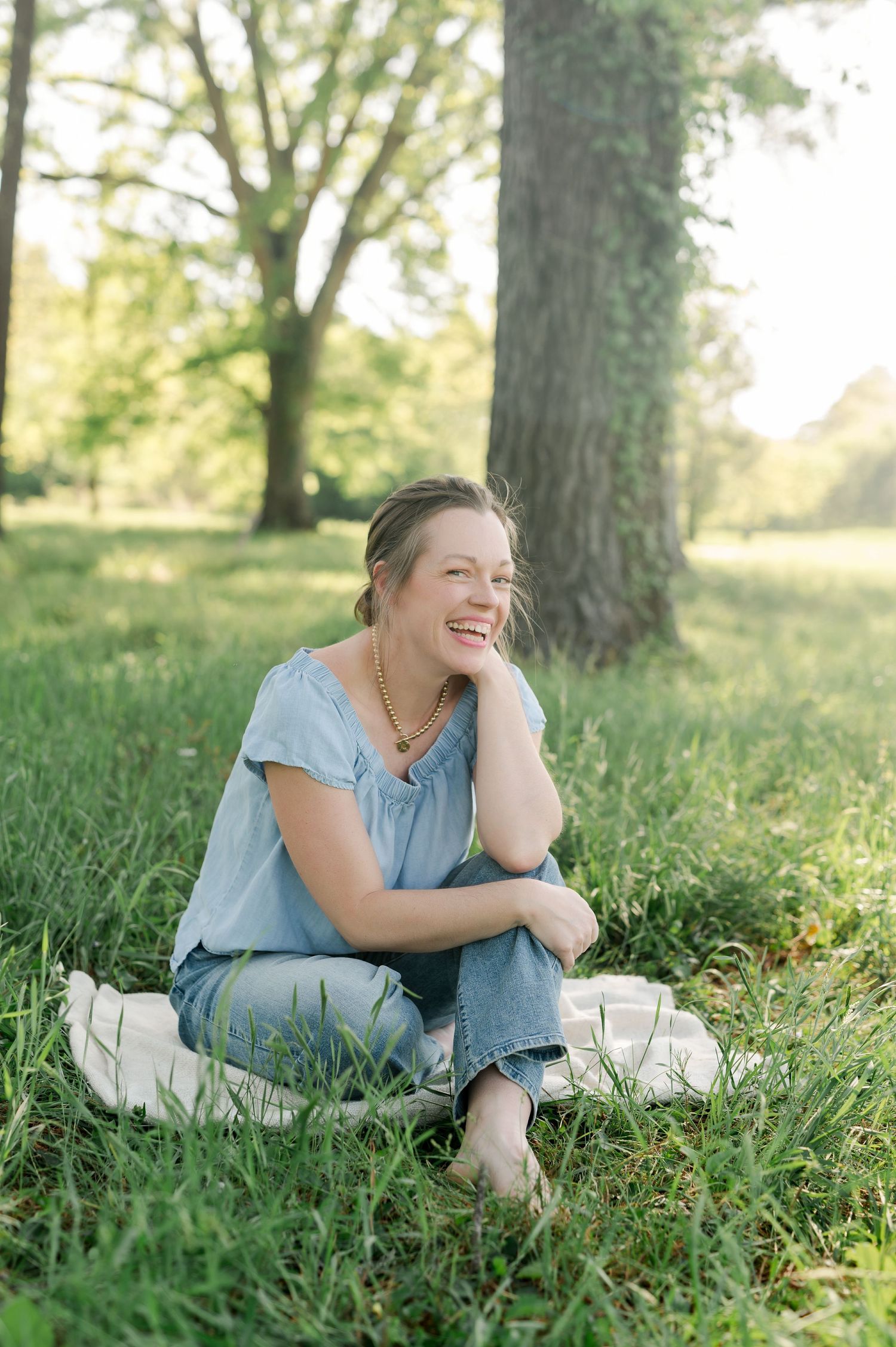 Woman in blue dress relaxing on grass in a sunny park setting.