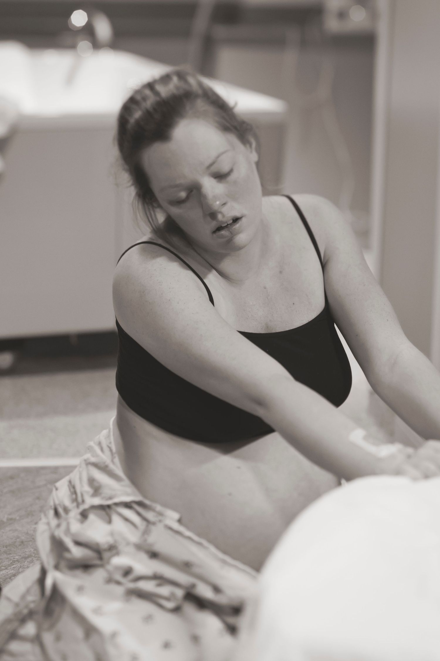 A pregnant patient works through labor pains on a hospital birthing ball.