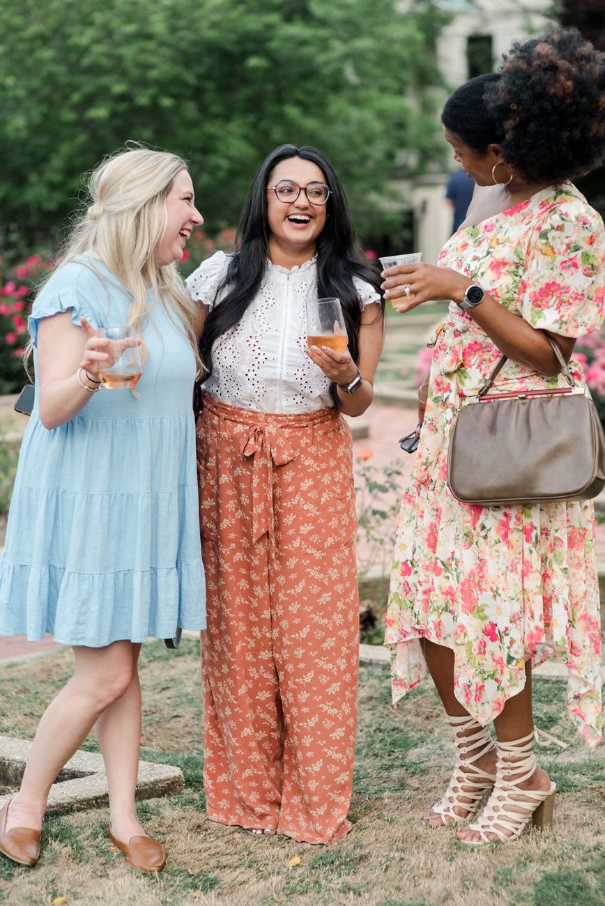 Group of people in summer dresses and floral outfits gathering outdoors.