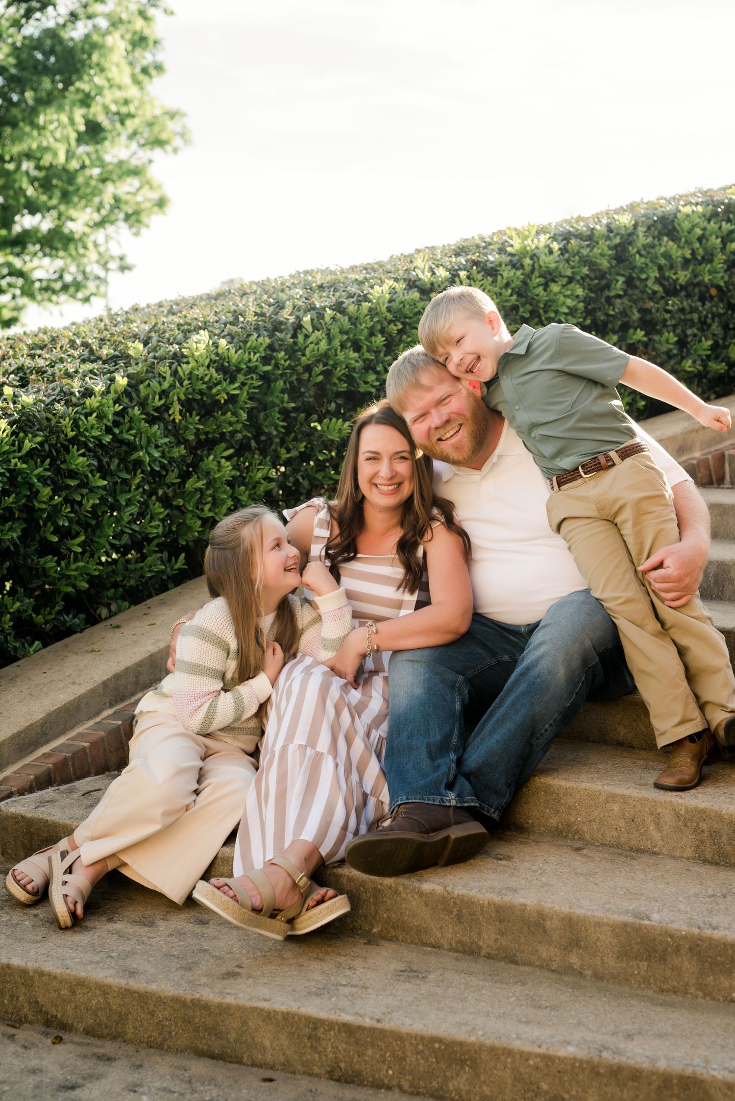 Family shares tender moments while relaxing on outdoor concrete steps.