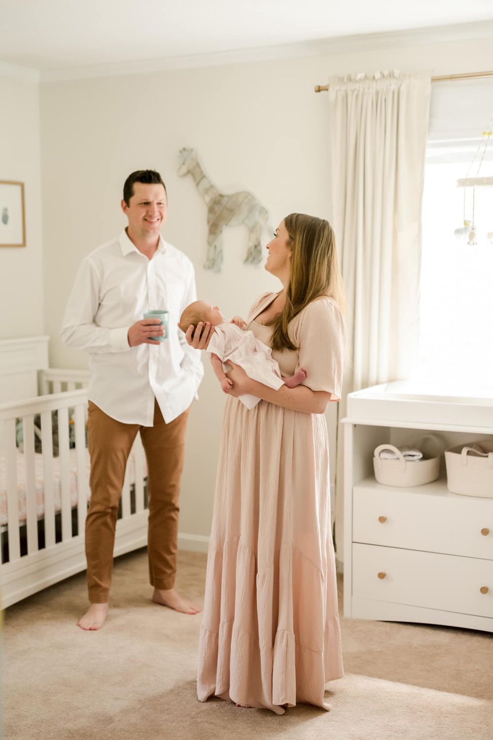 Family sharing intimate moment with newborn on white couch.