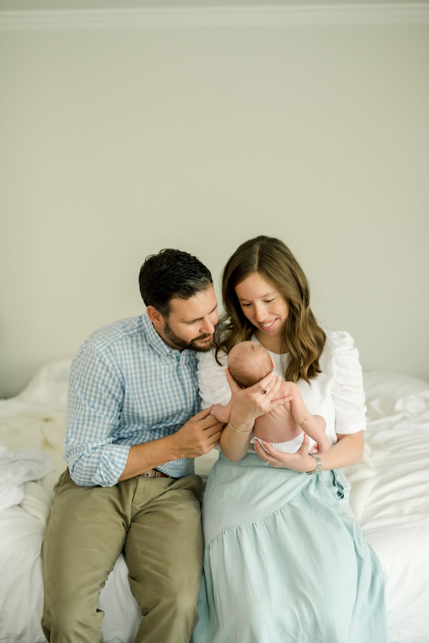 Family sitting together on bed sharing intimate moment with their newborn baby.