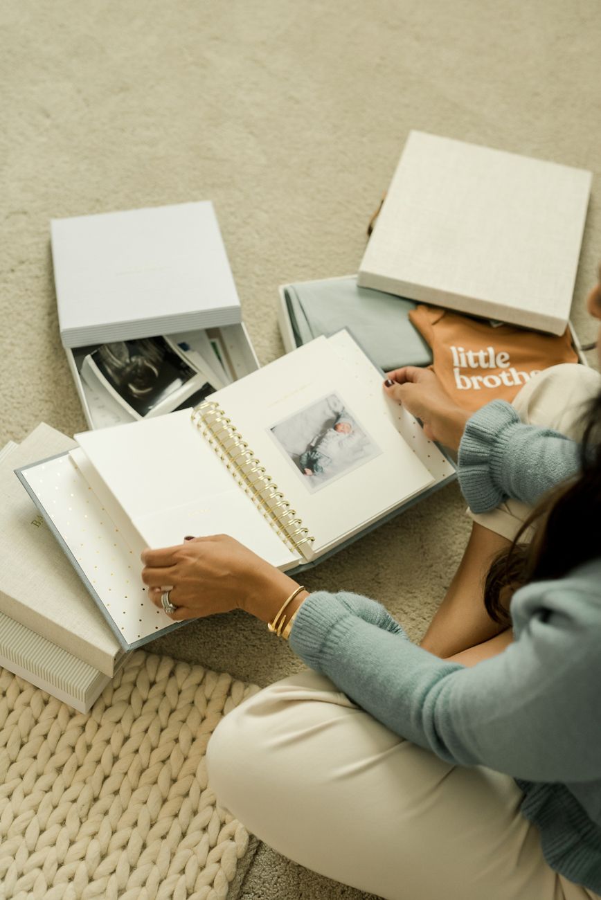 Hands flipping through pages of a photo album or scrapbook on a textured surface.