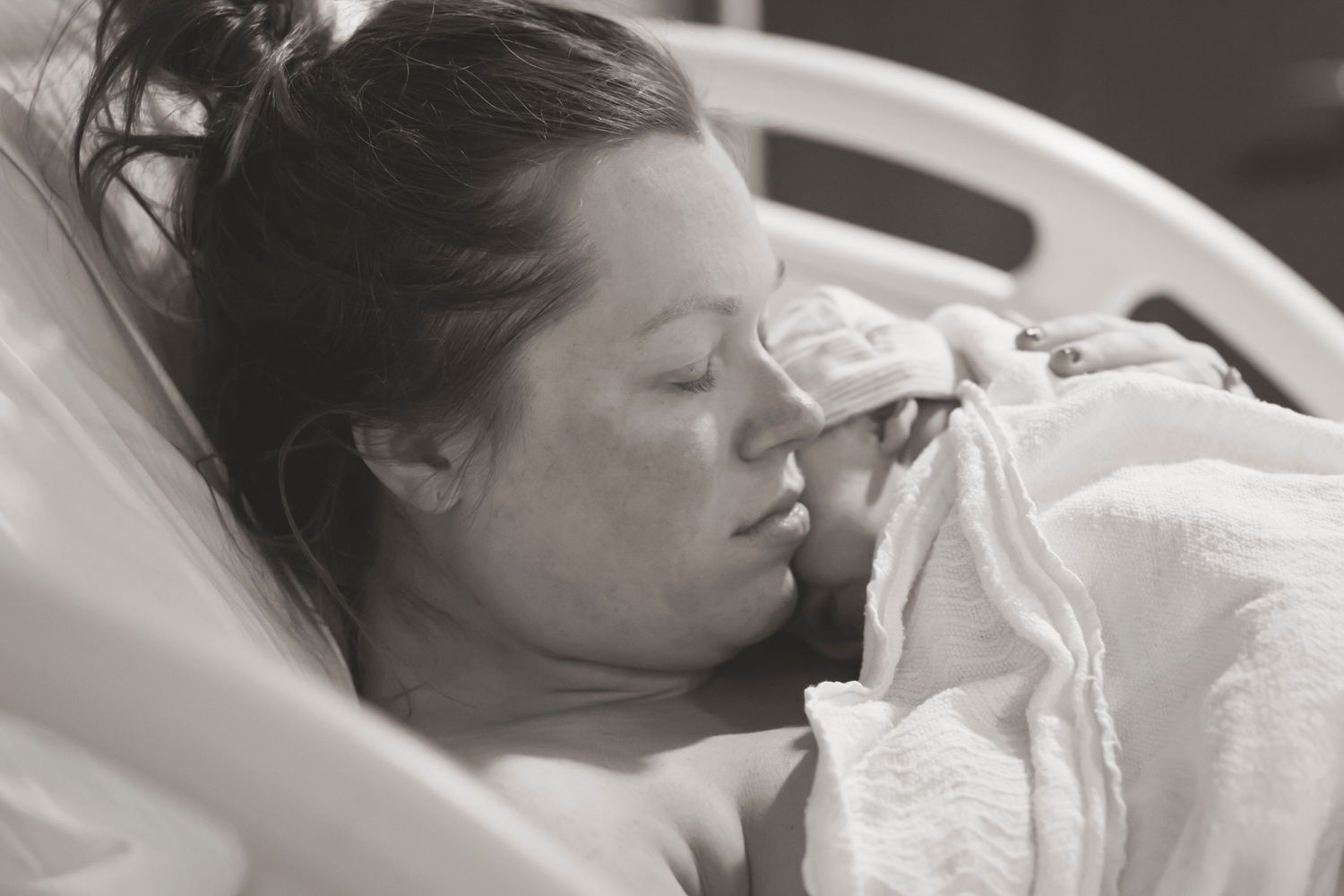 An exhausted patient rests in a hospital bed with white linens and medical equipment.