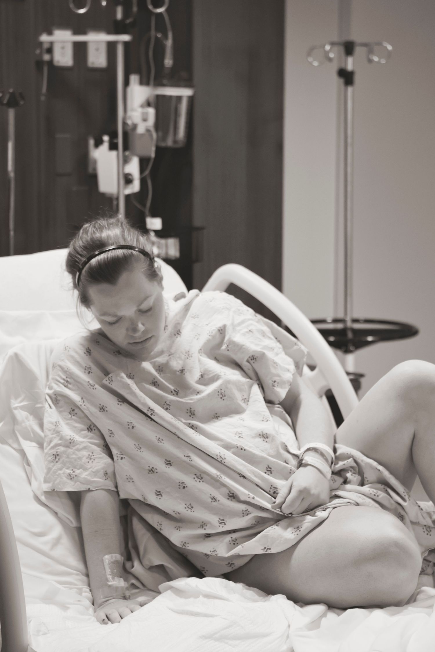 A pregnant patient in a hospital gown rests on a hospital bed during labor.