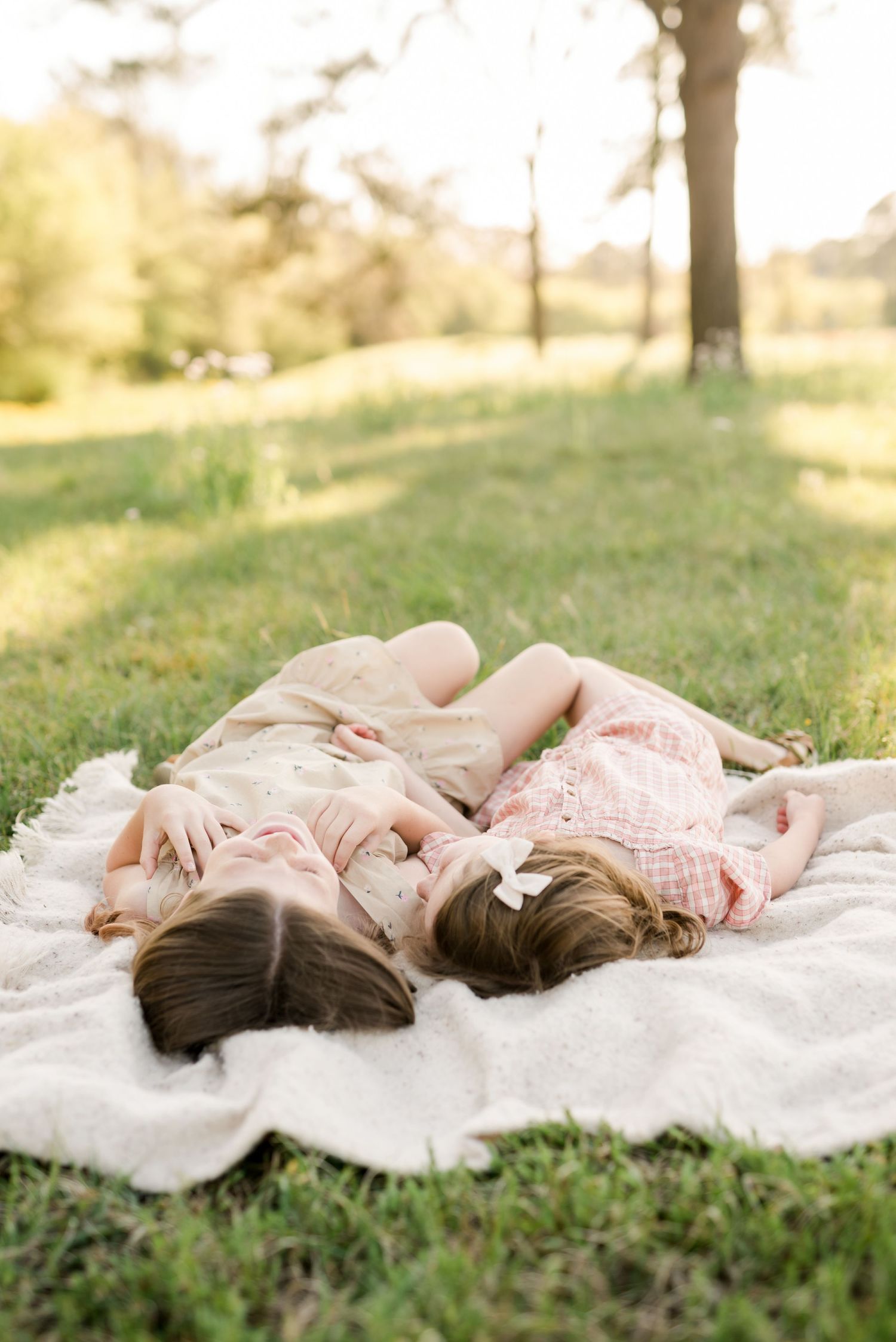 Two people lying on a blanket in the grass during golden hour.