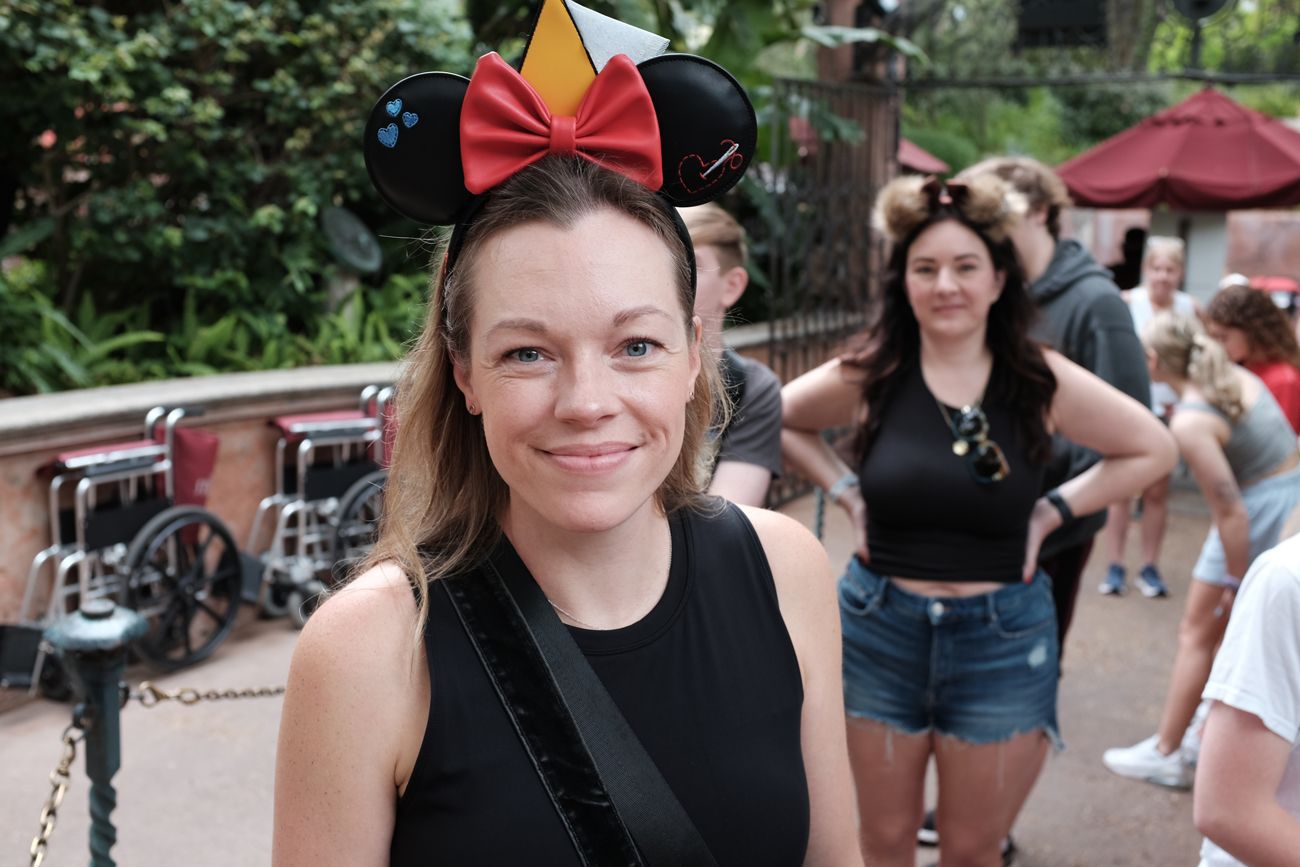 Theme park visitor wearing Mickey Mouse ears and black tank top.