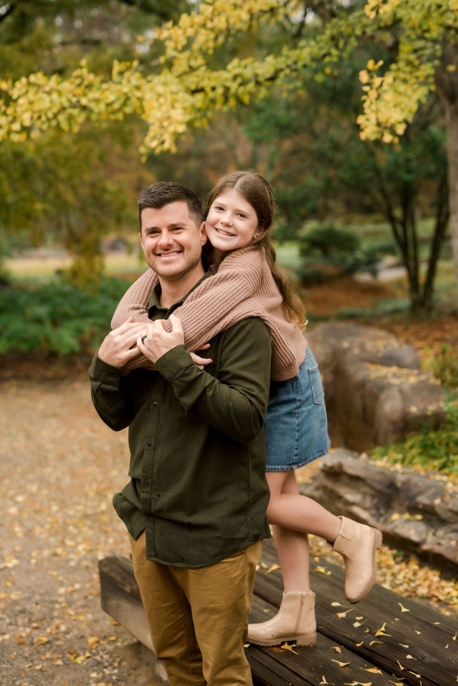Playful piggyback ride moment captured in a scenic fall garden setting.