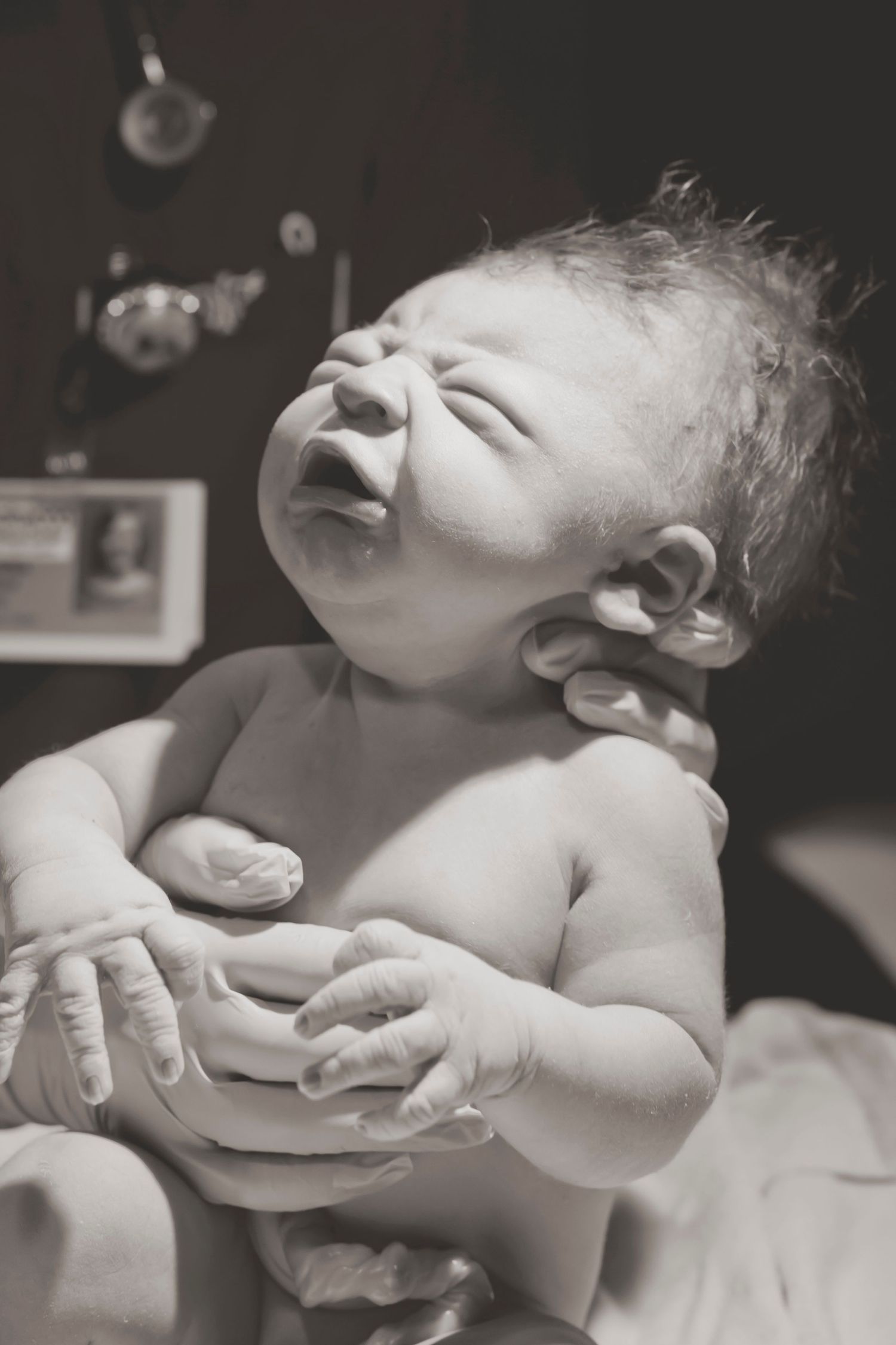 Black and white portrait of a newborn baby with eyes closed and wispy hair.