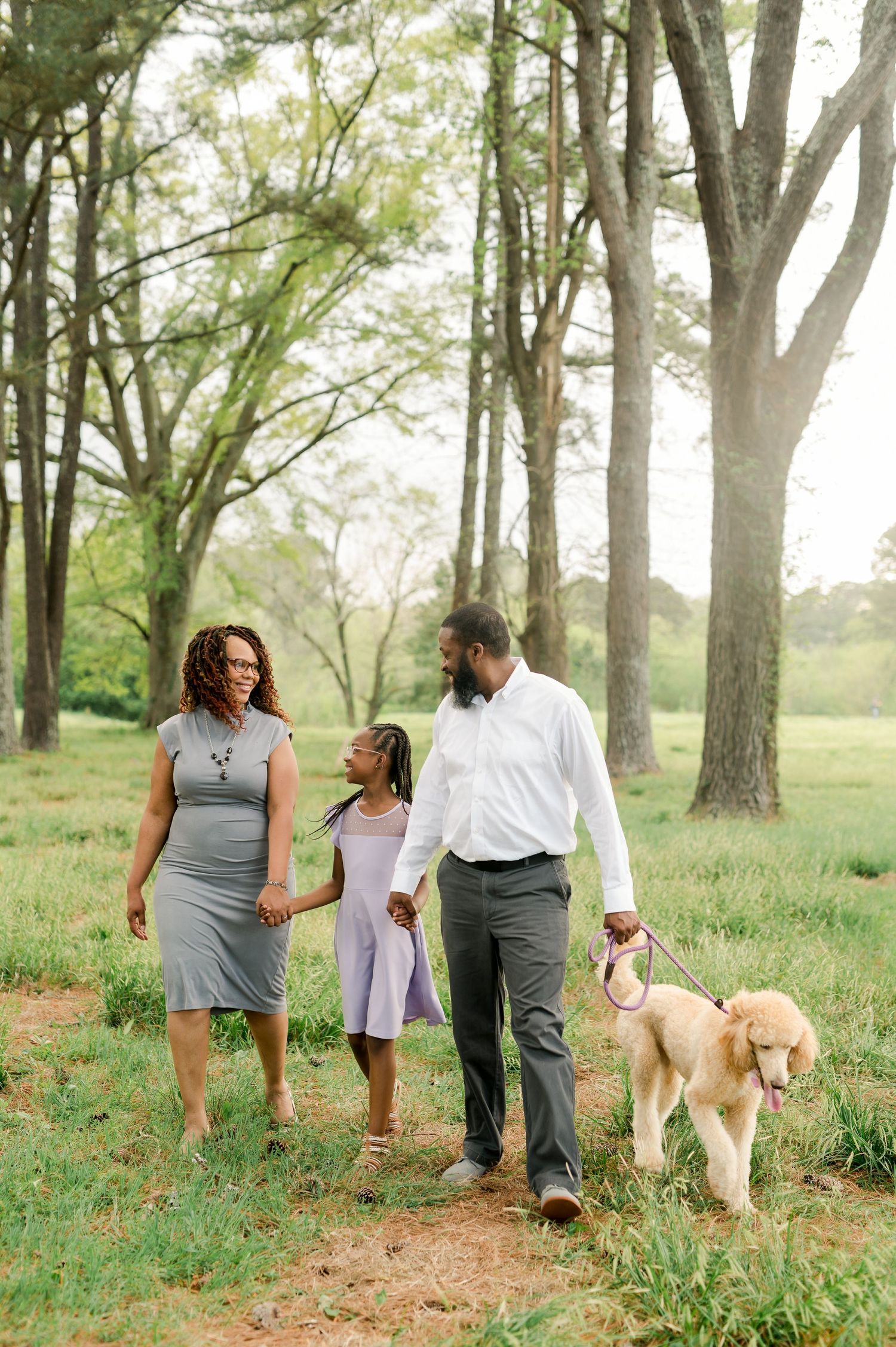 Family walks together with their golden retriever dog through a scenic wooded area.