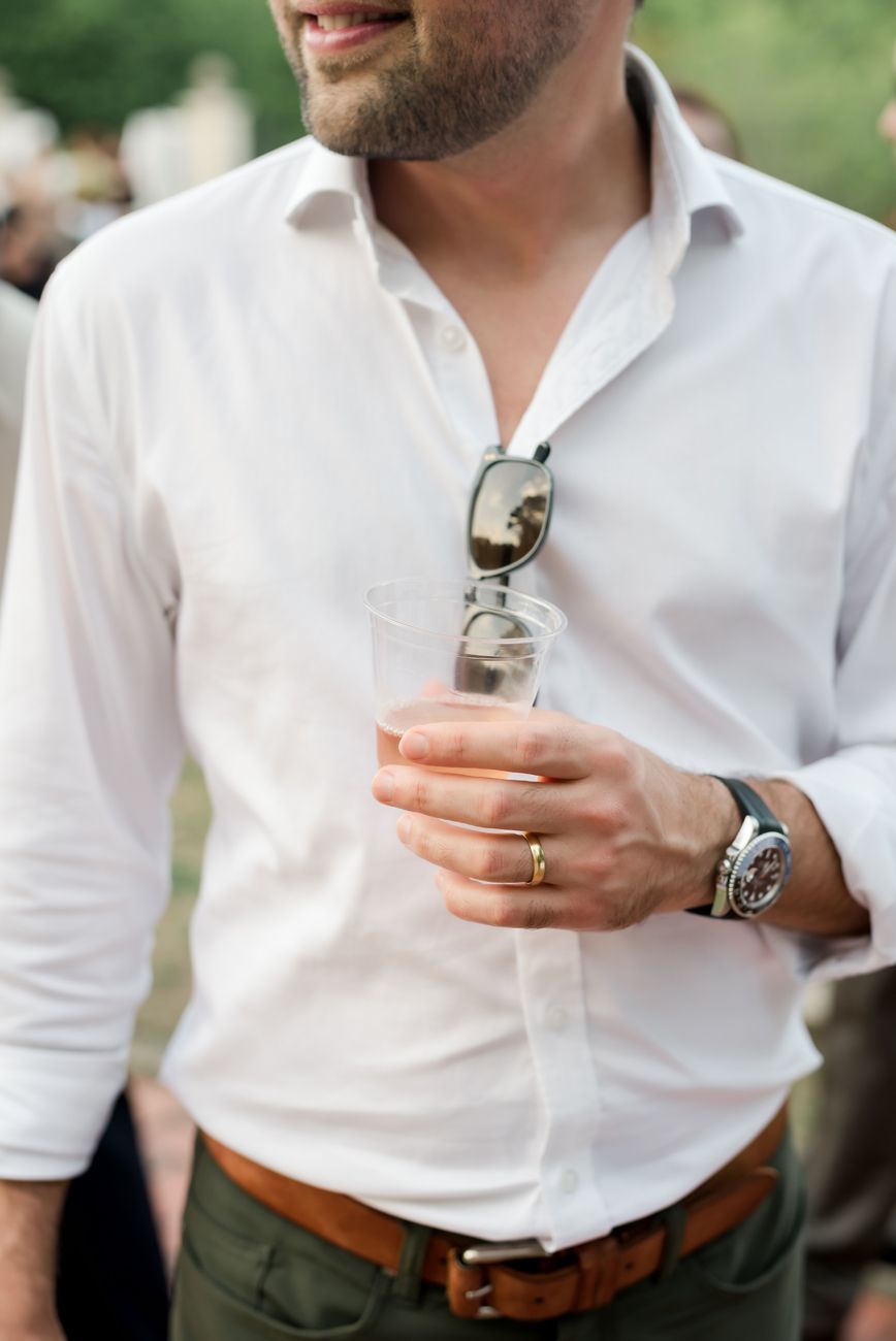 Close-up of person in white dress shirt holding a beverage.