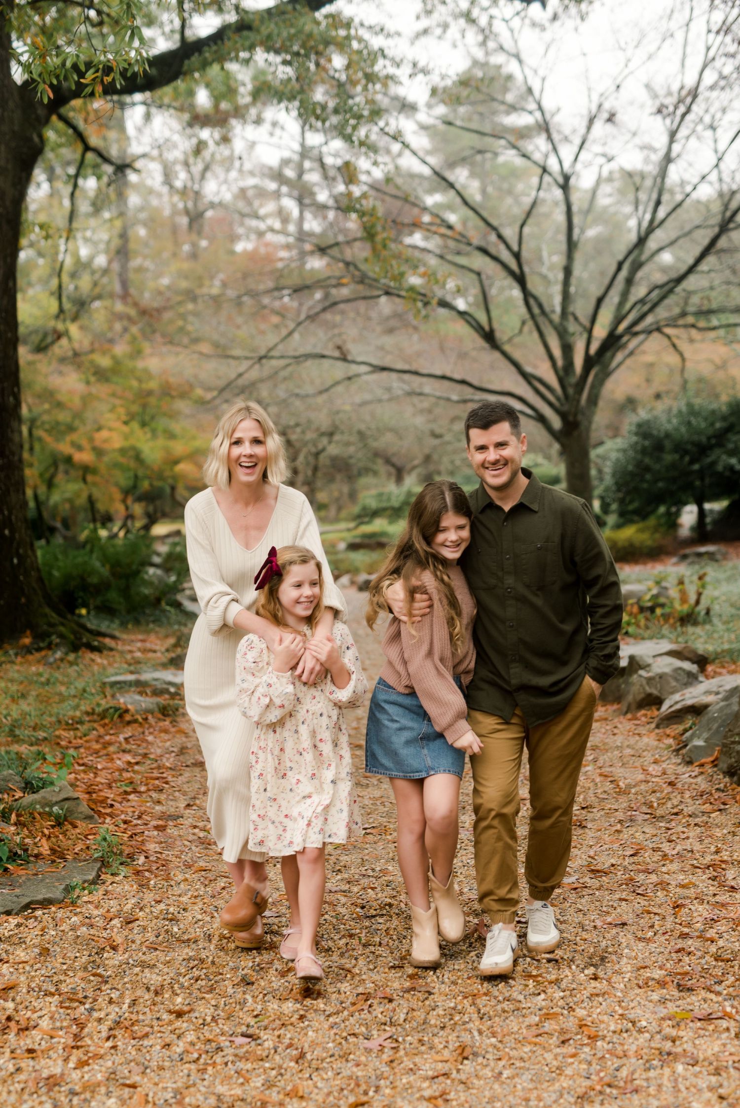 Family walking together on autumn path surrounded by colorful fall foliage.