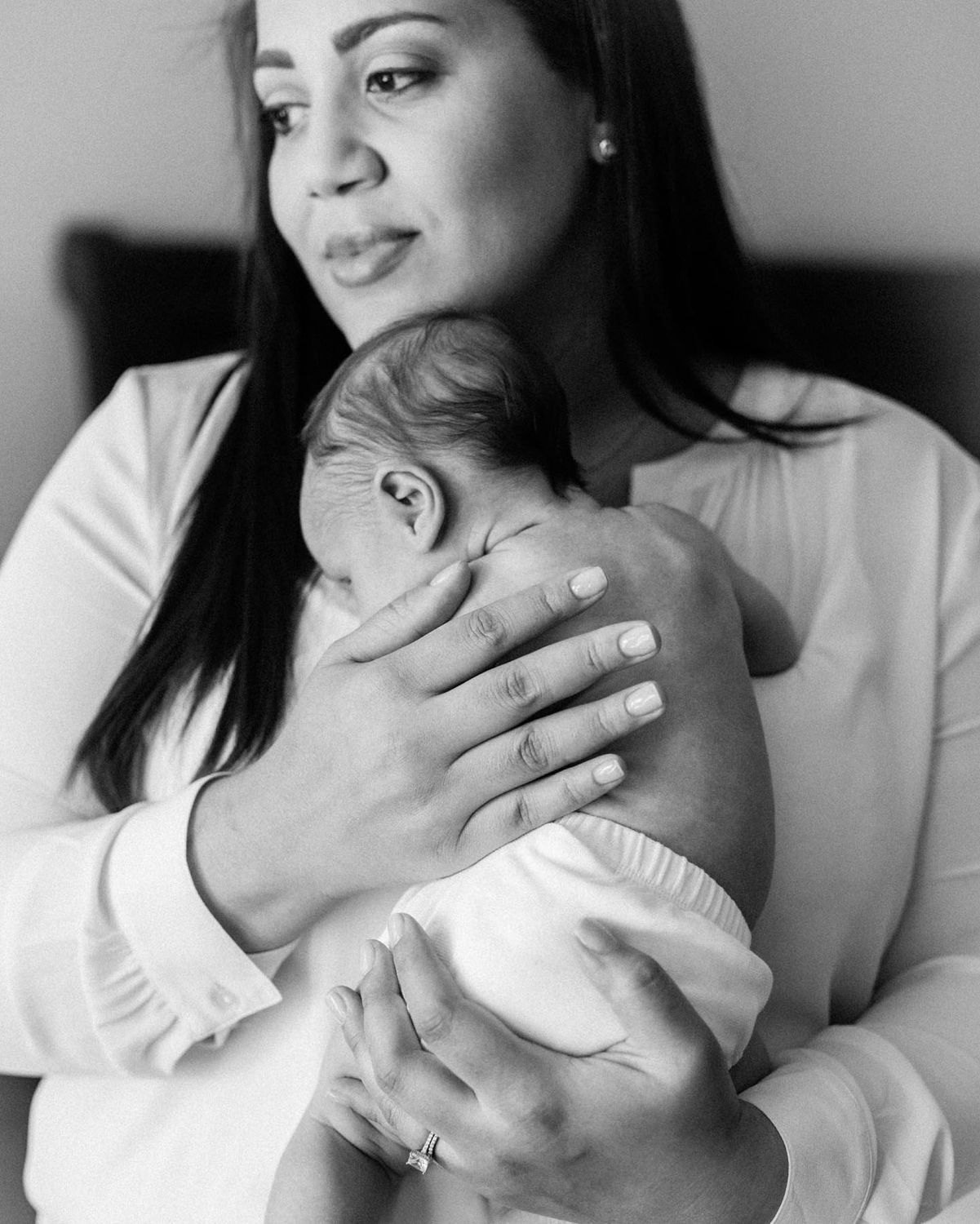A black and white portrait shows a tender moment between parent and newborn.