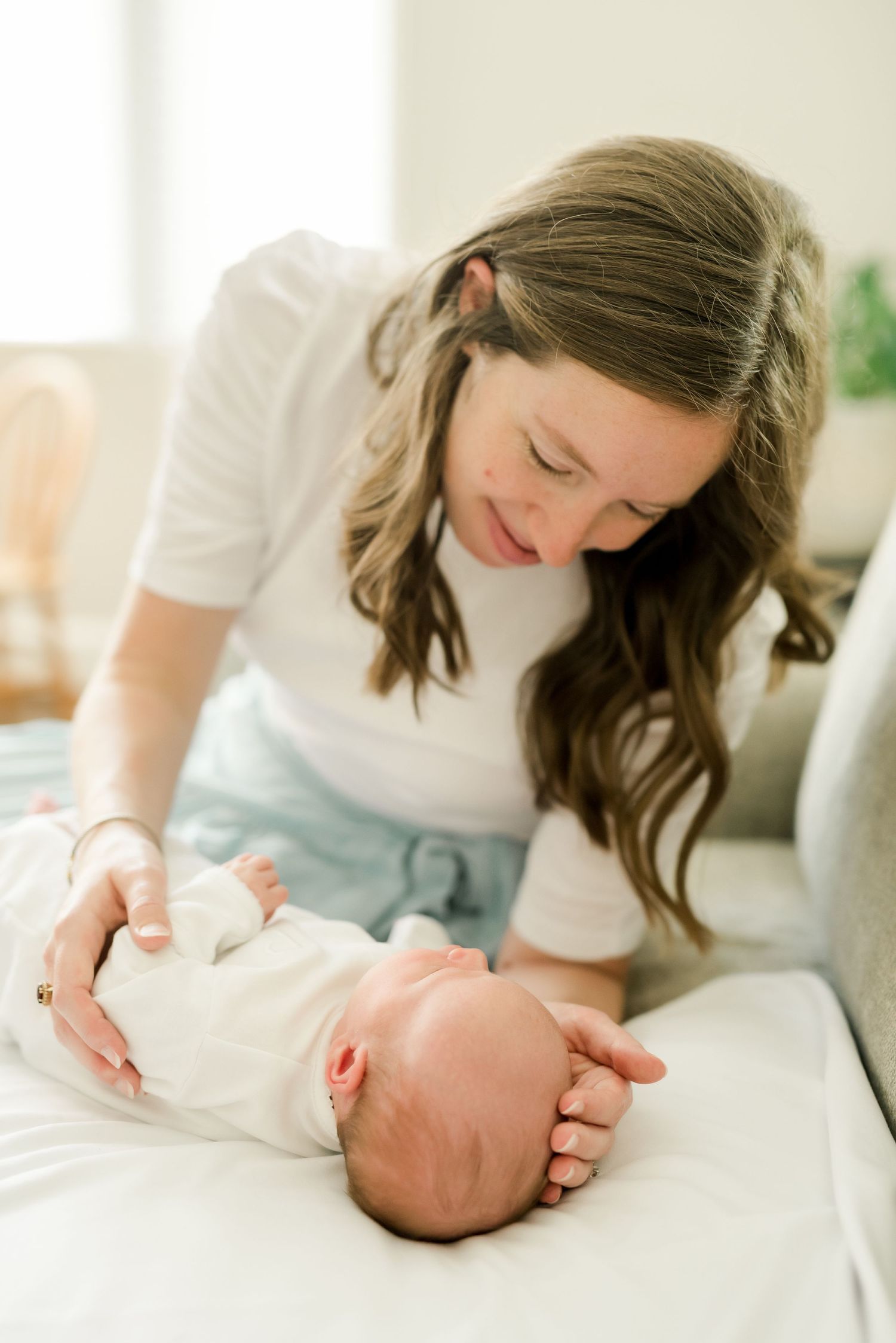 Gentle moment captured between parent and baby on light colored couch.